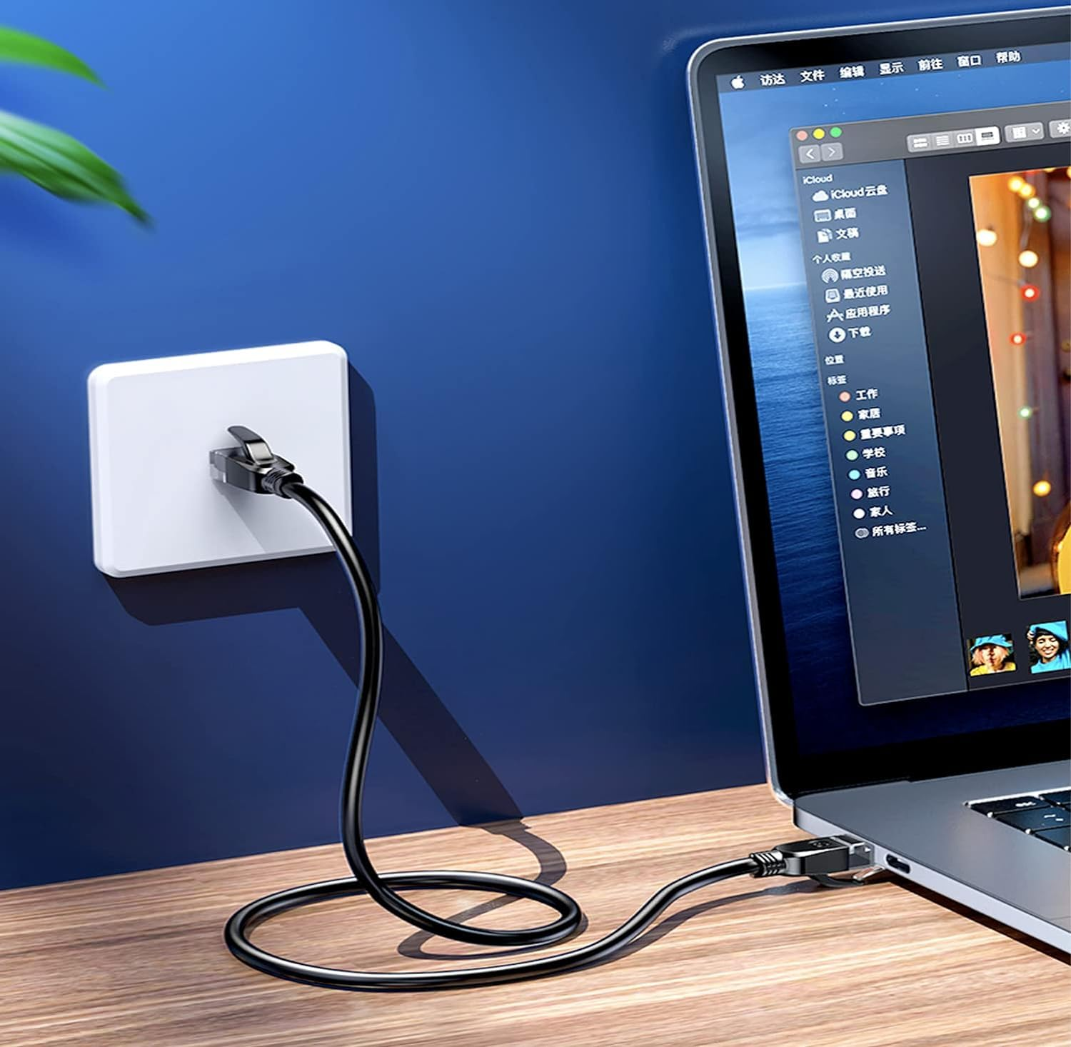 Ein schwarzes Kabel wird von einer Steckdose in einen Laptop gesteckt.
