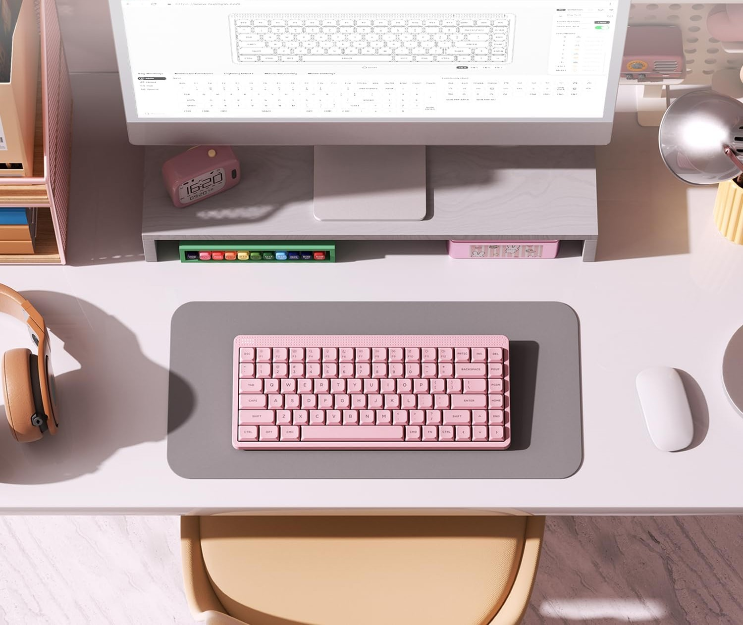 Różowa klawiatura mechaniczna na szarej macie obok białej myszy.