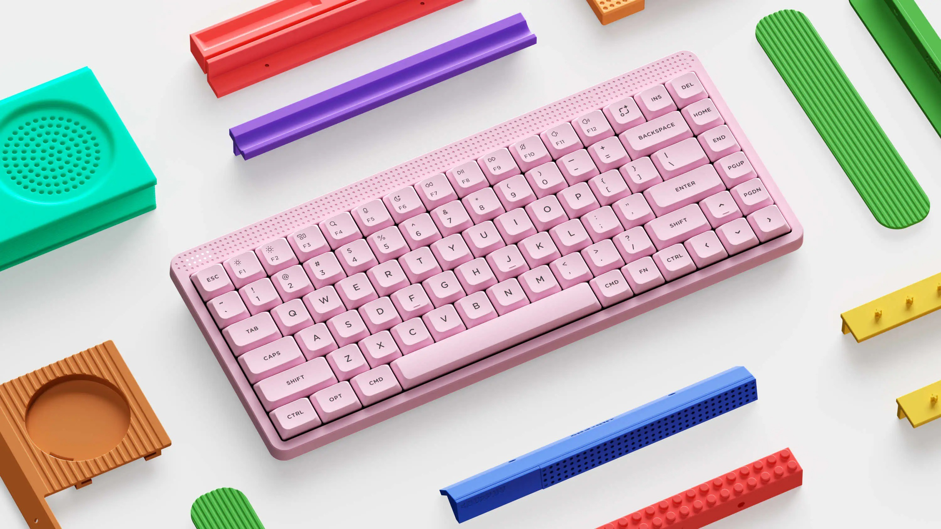 Różowa klawiatura bezprzewodowa na białym tle, otoczona kolorowymi klockami.
