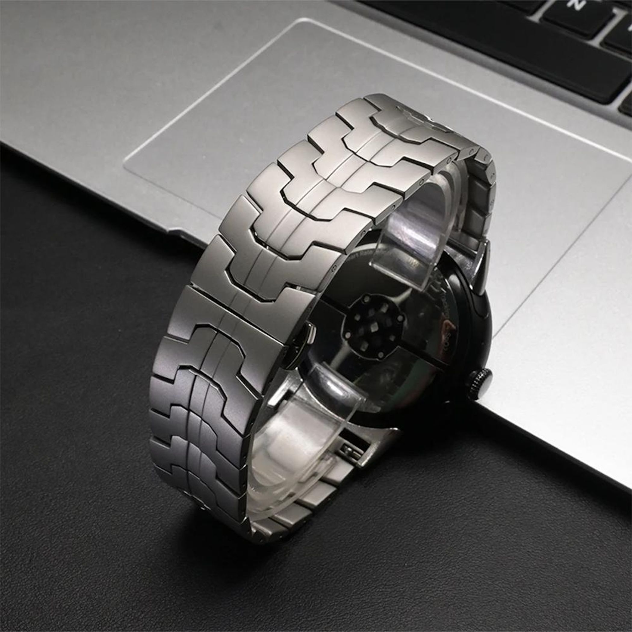 Silbernes Armbanduhr auf einem Laptop mit schwarzer Tastatur.