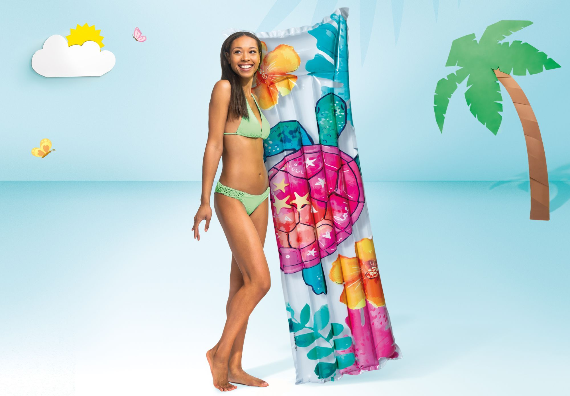 Kobieta w bikini trzyma nadmuchiwaną żółwicę z kwiatami na niebieskim tle.