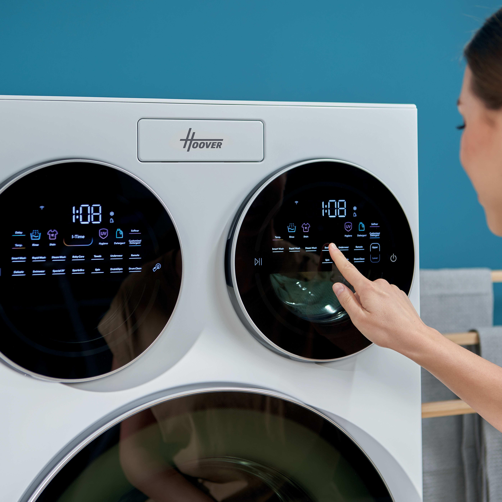 Eine Frau wählt ein Programm auf einer weißen Waschmaschine mit Touchscreen-Bedienfeld.
