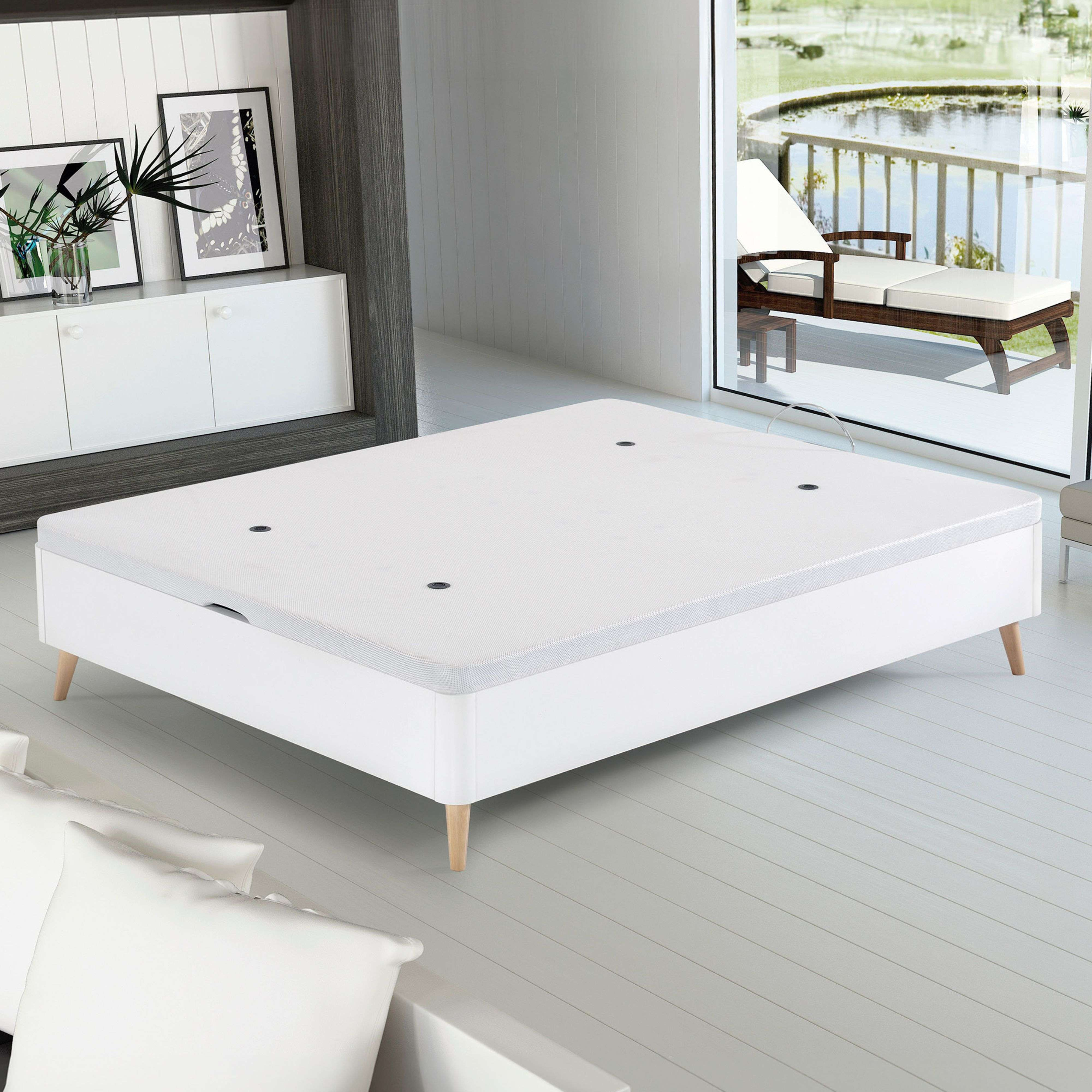 Una base de cama blanca con patas de madera sobre suelo de madera.
