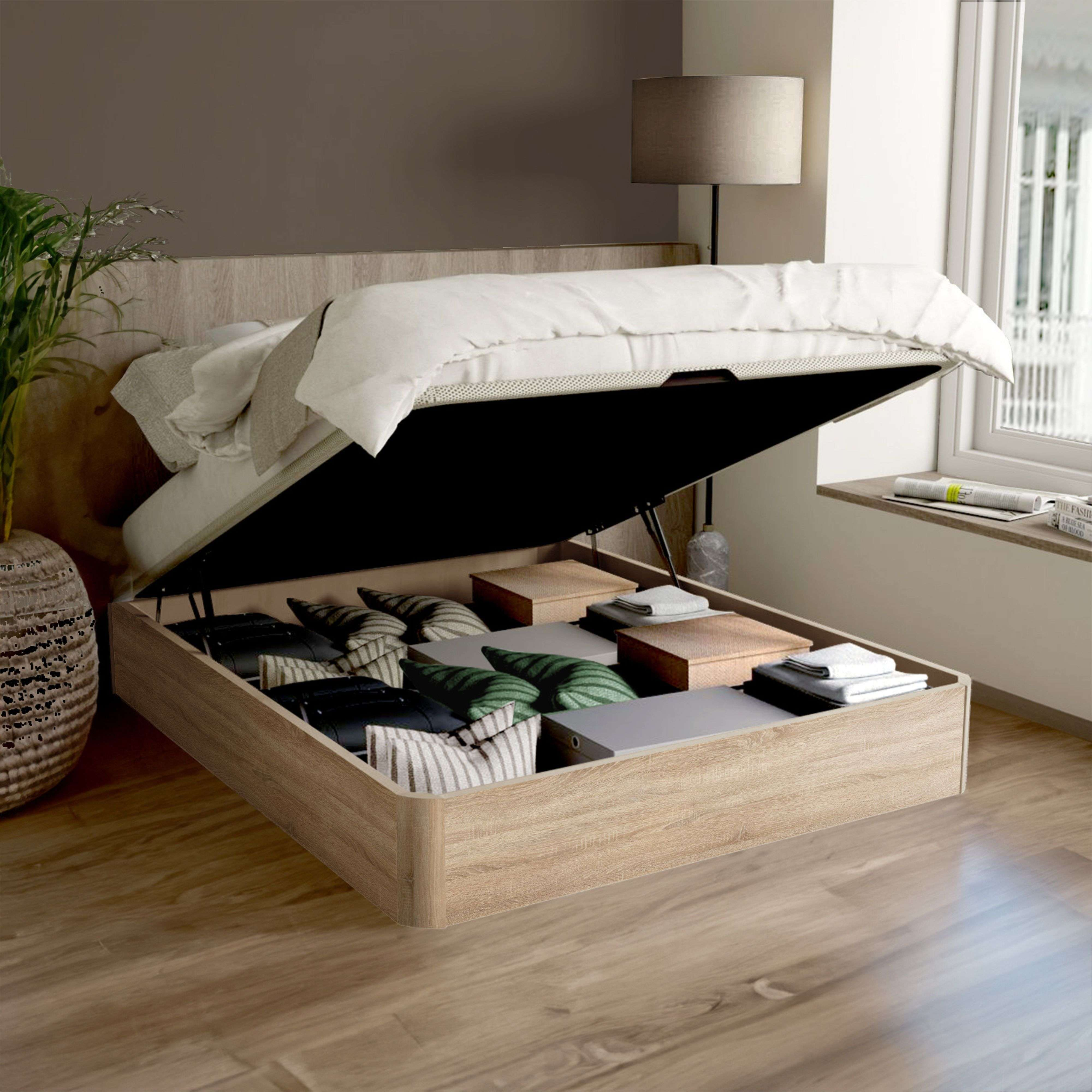 Cama con compartimento de almacenamiento abierto, lleno de cojines y mantas. Suelo de madera.