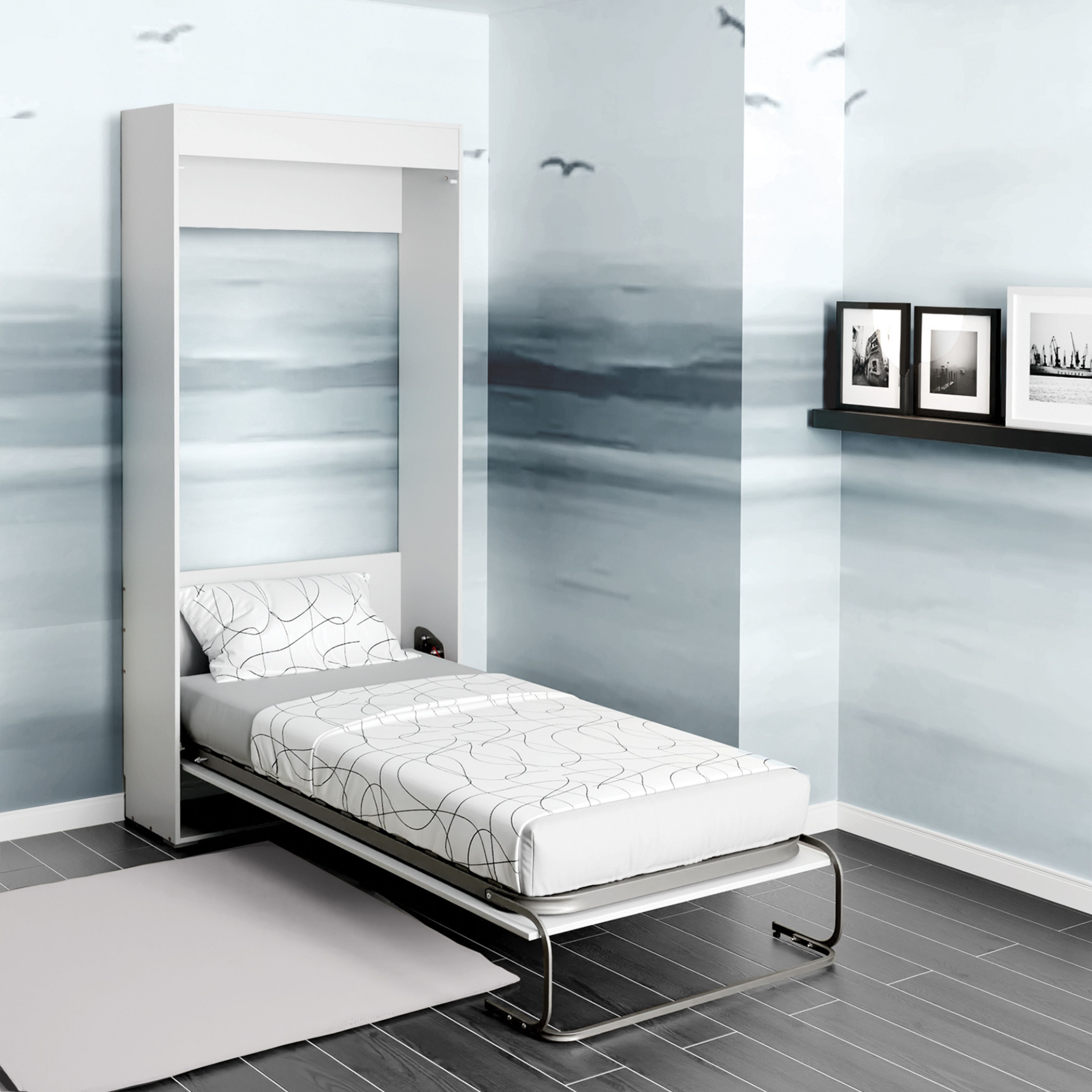 Una cama abatible blanca está abierta con edredón y almohada estampados. Una alfombra sobre suelo de madera oscura.