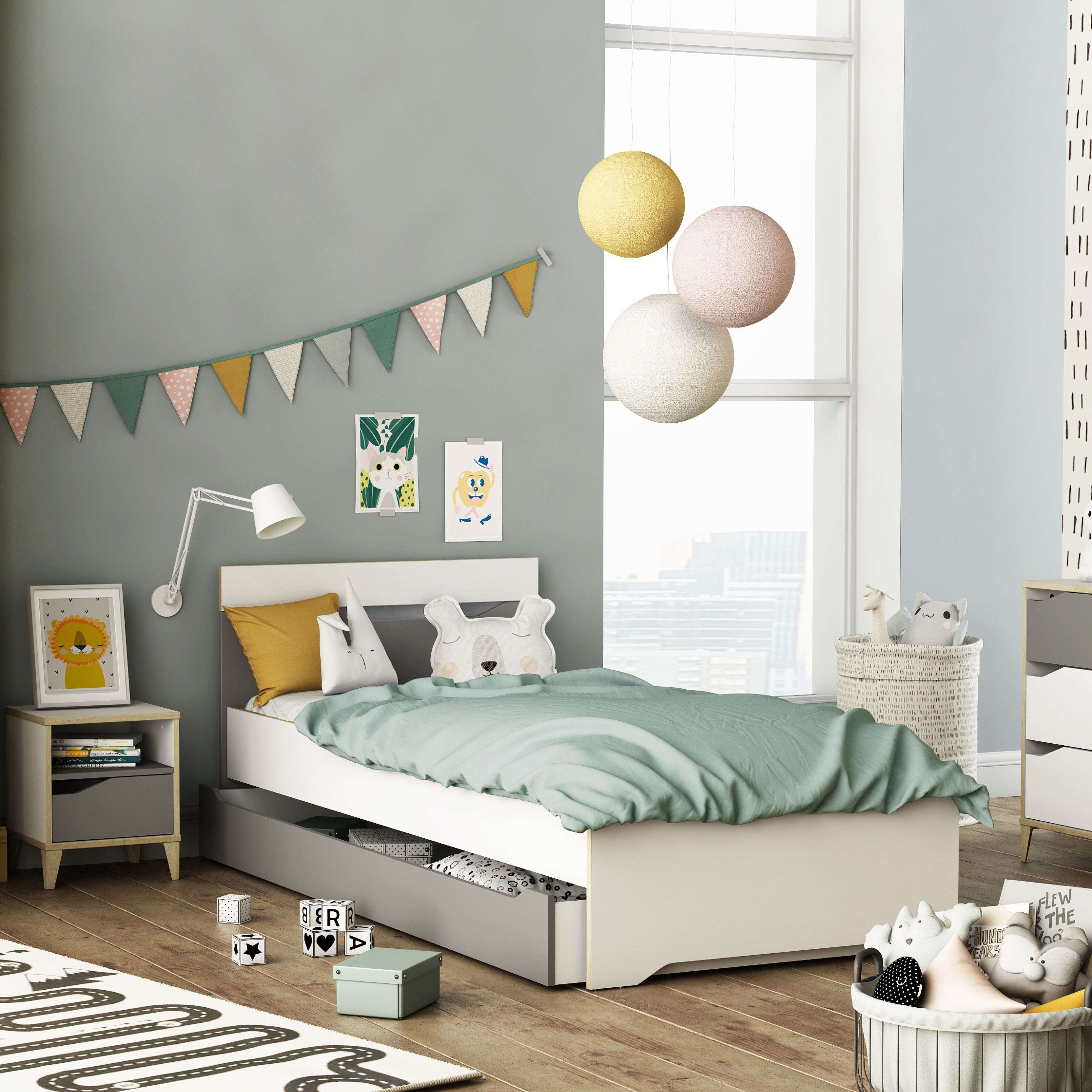 Dormitorio infantil con cama, mesita de noche, cestas de juguetes y guirnalda.