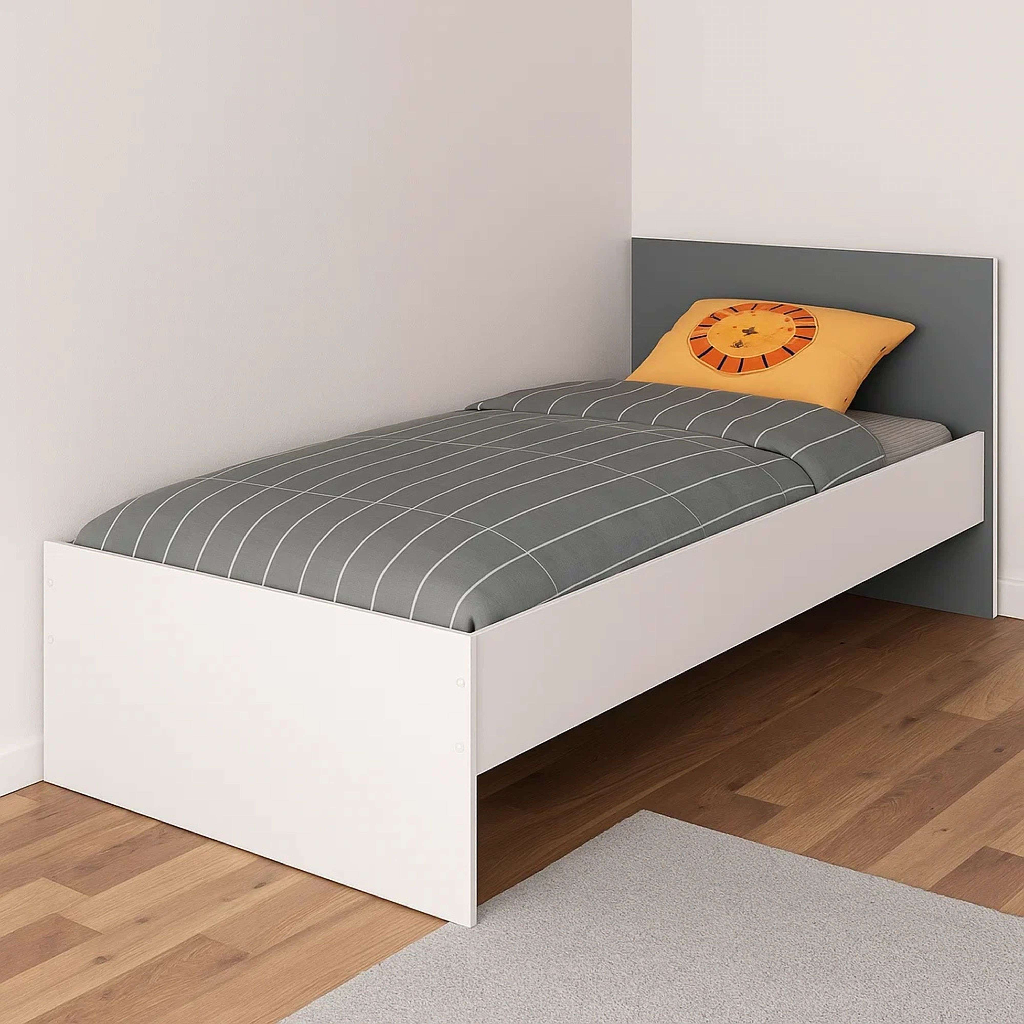 Una cama blanca con ropa de cama a cuadros grises y un cojín con motivo de león.
