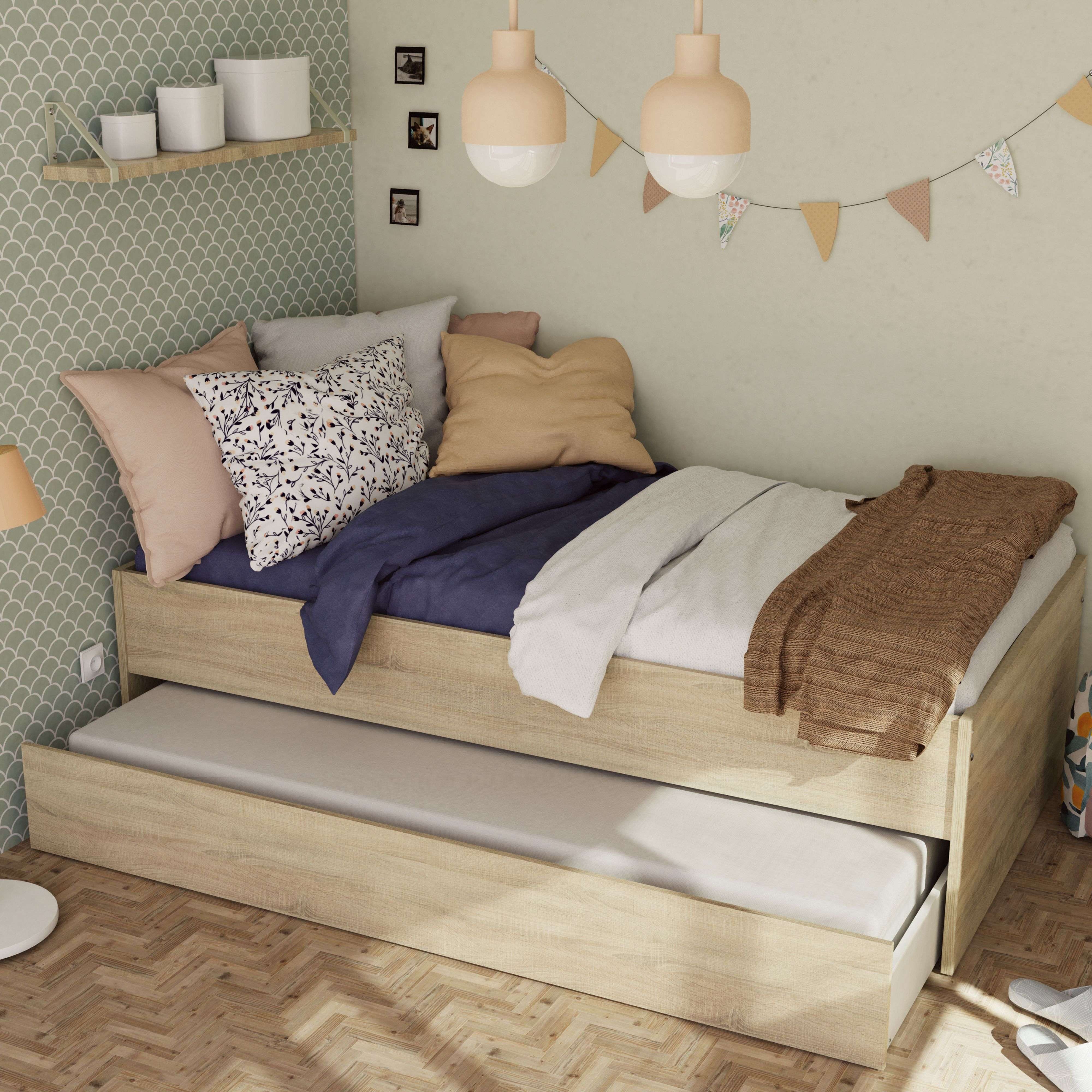 Cama de día de madera con cama nido, cojines y manta.