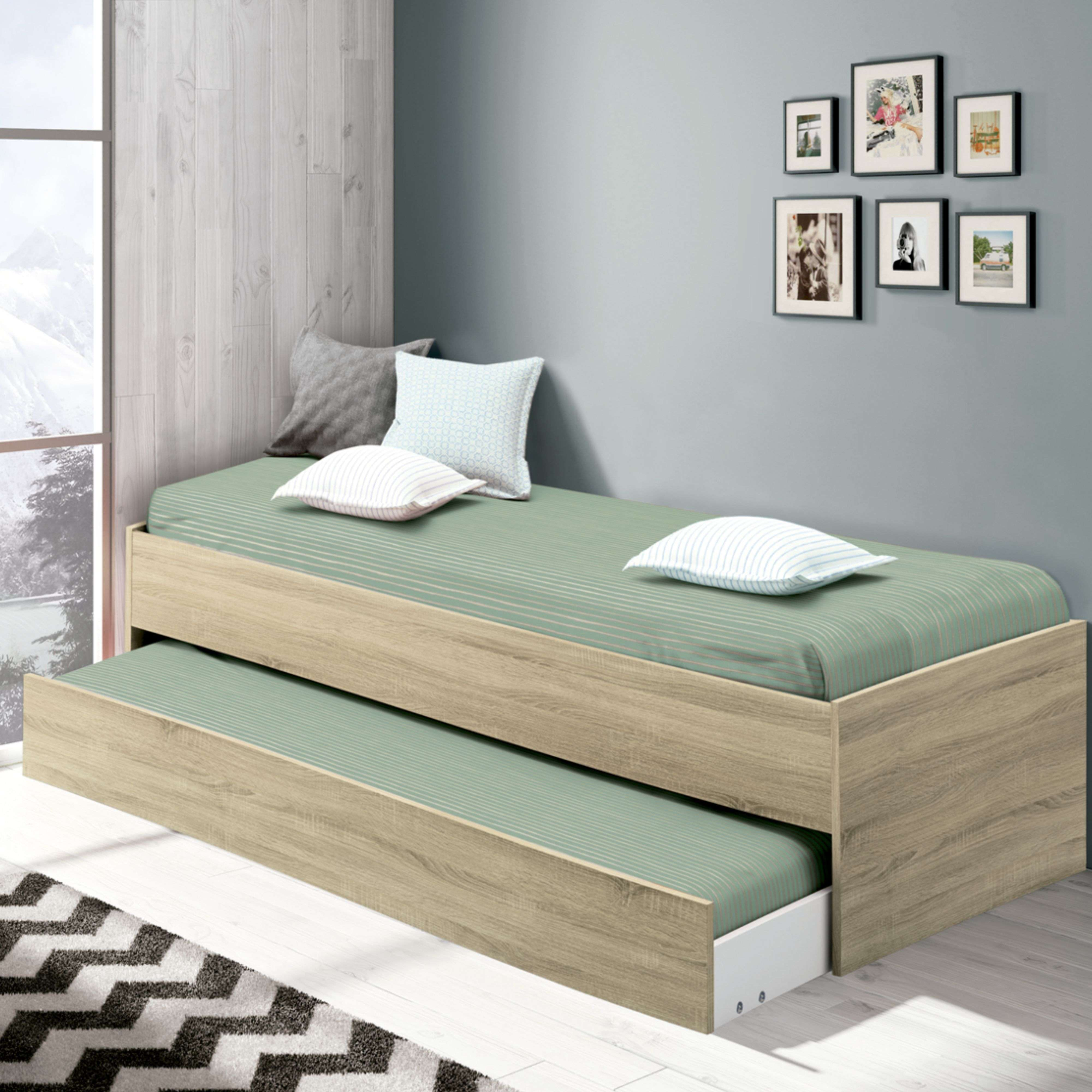 Una cama nido con sábanas verdes, cojines y cuadros en la pared.