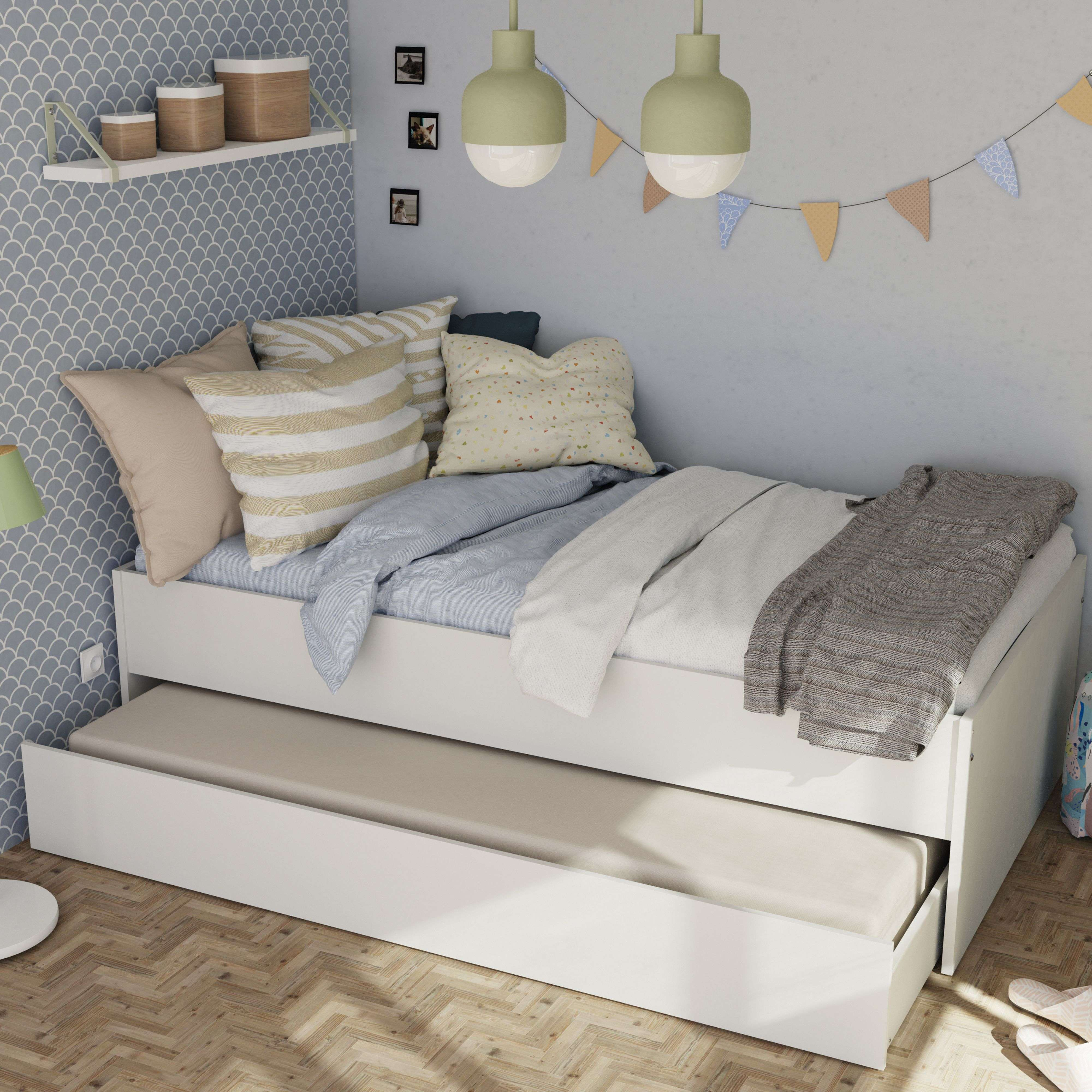 Un diván blanco con cama nido, cojines y mantas sobre suelo de madera.