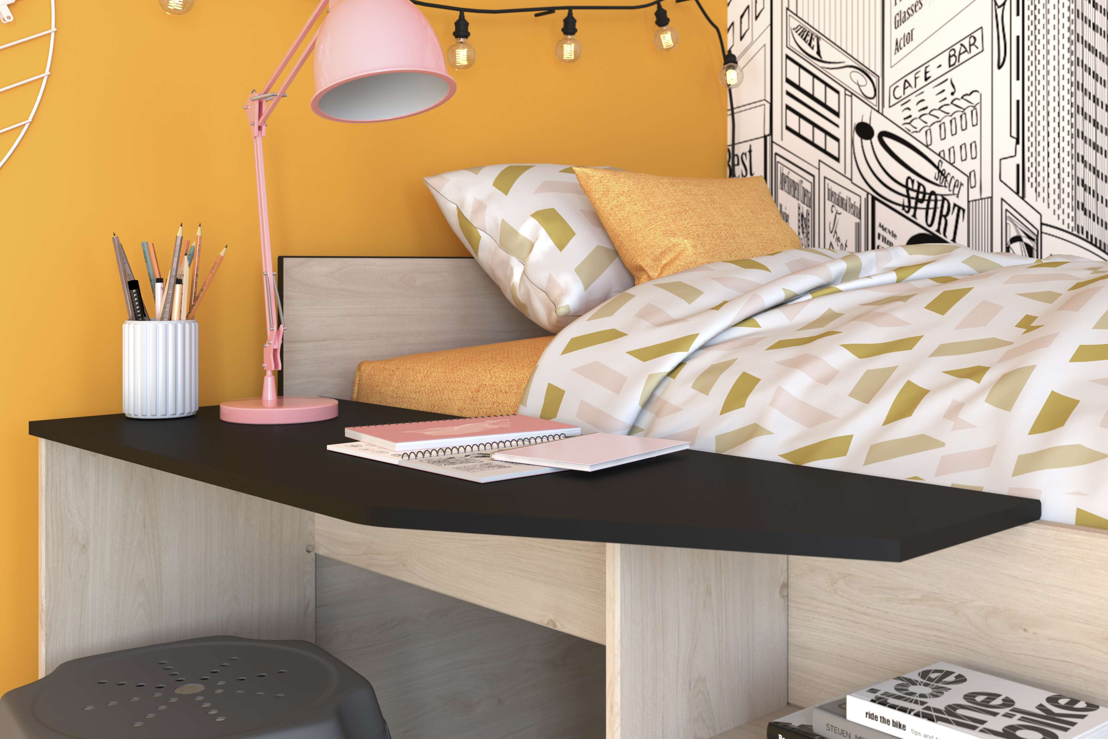 Un escritorio con libros, bolígrafos, una lámpara y una cama con almohadas estampadas.