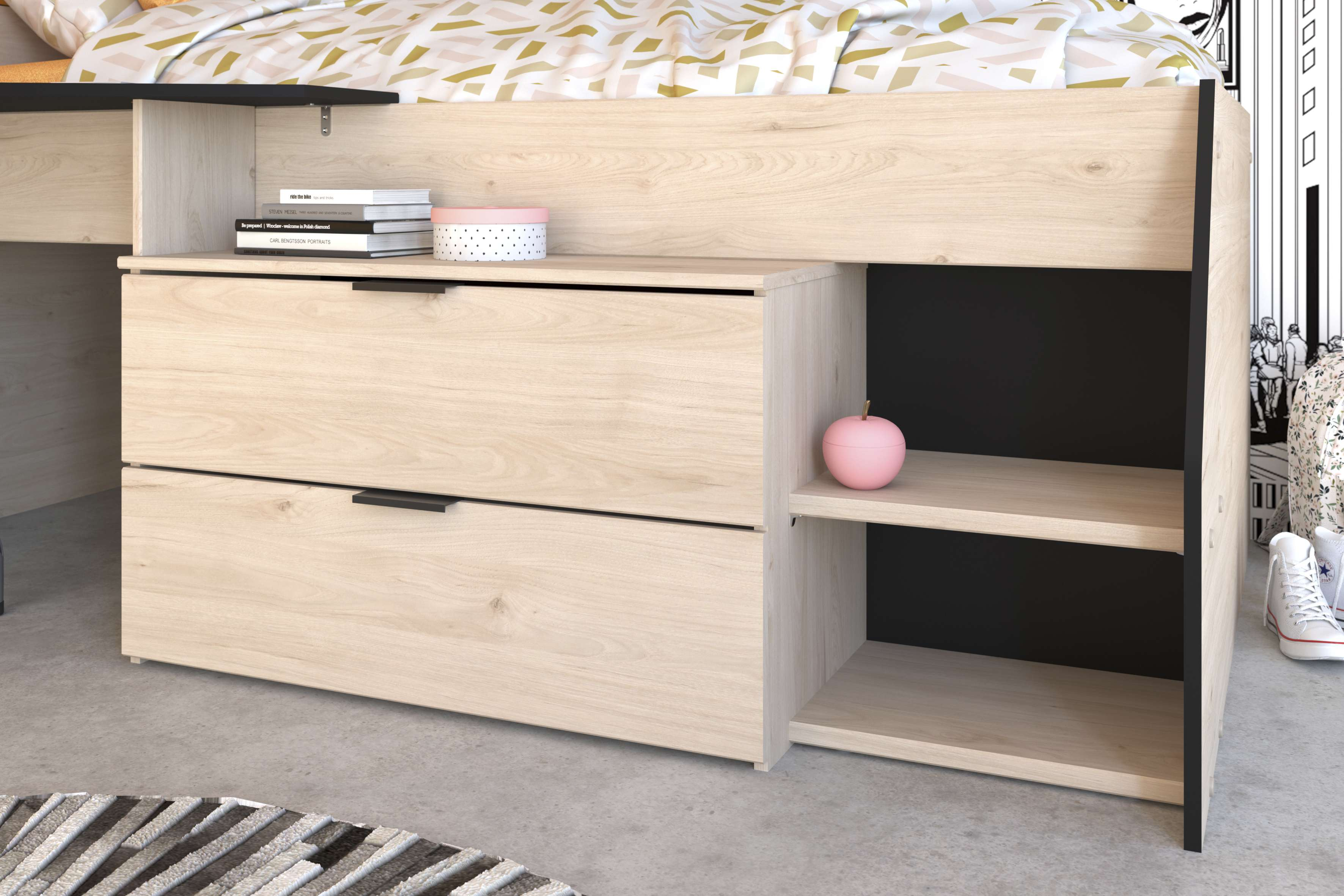 Cama-armario de madera clara con dos cajones, libros, una caja redonda y una manzana rosa.