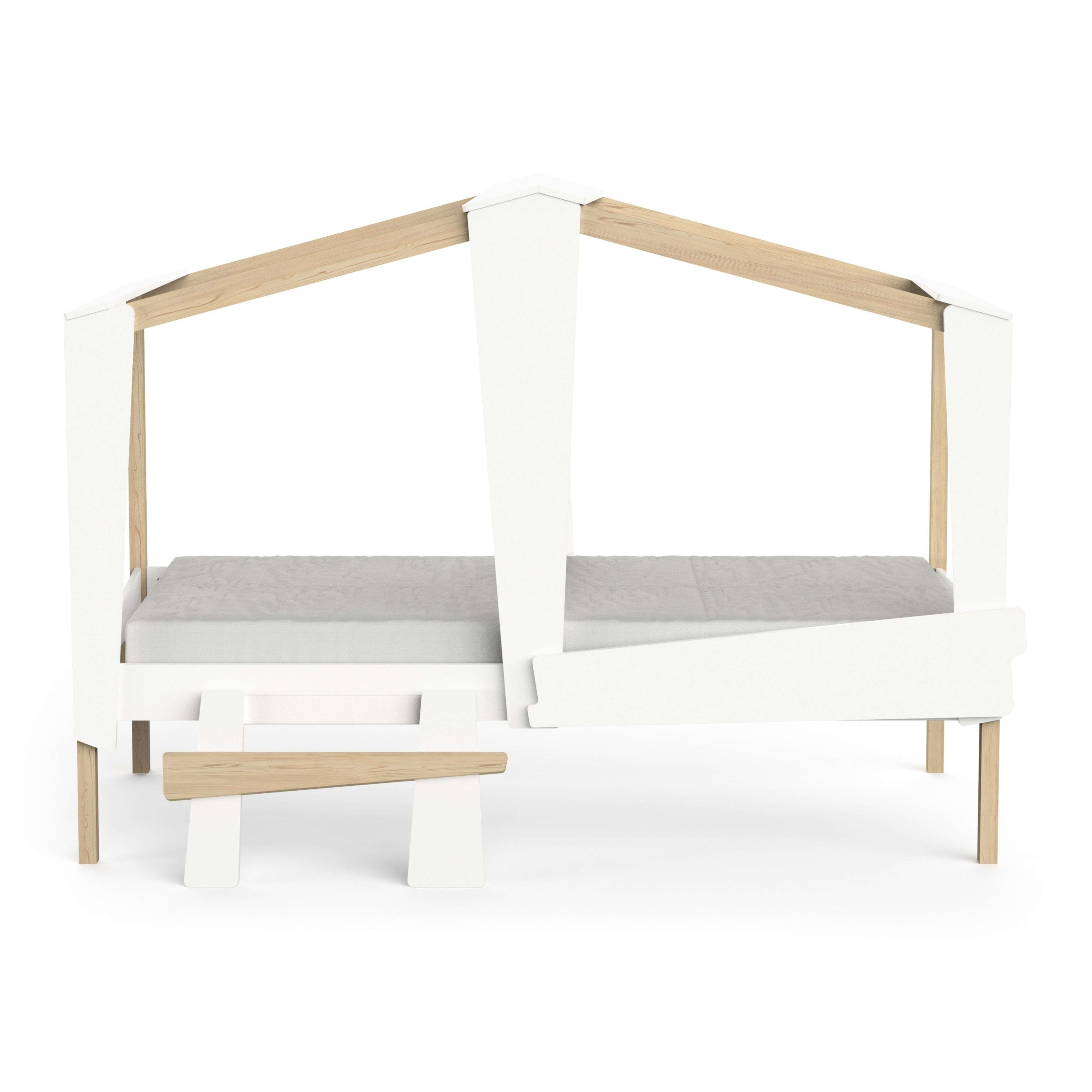 Una cama blanca con forma de casa, detalles en madera y colchón gris.