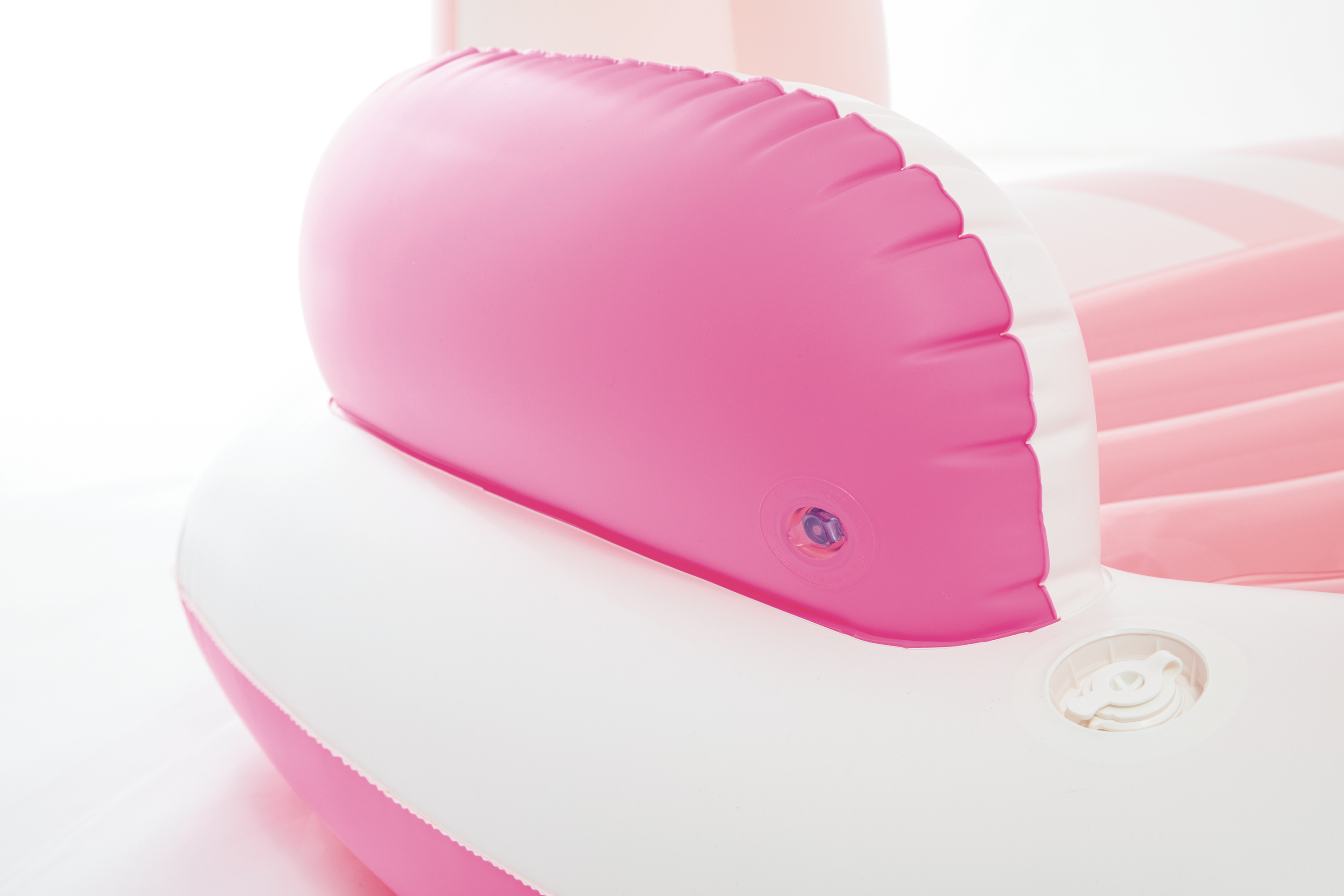 Nahaufnahme eines aufblasbaren Objekts in Rosa und Weiß, möglicherweise ein Stuhl oder eine Liege.