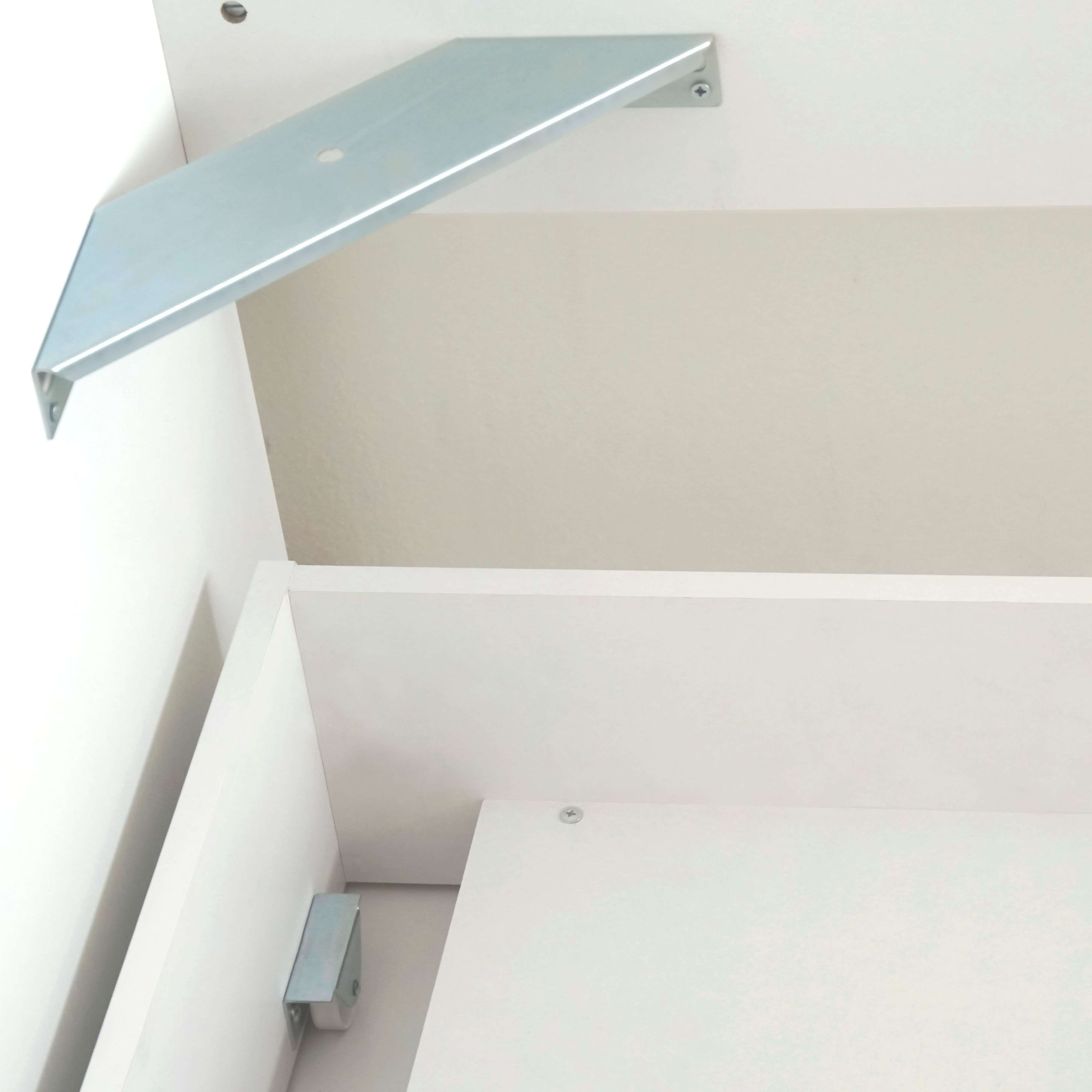 Un soporte plateado fijado a una superficie blanca con tornillos.