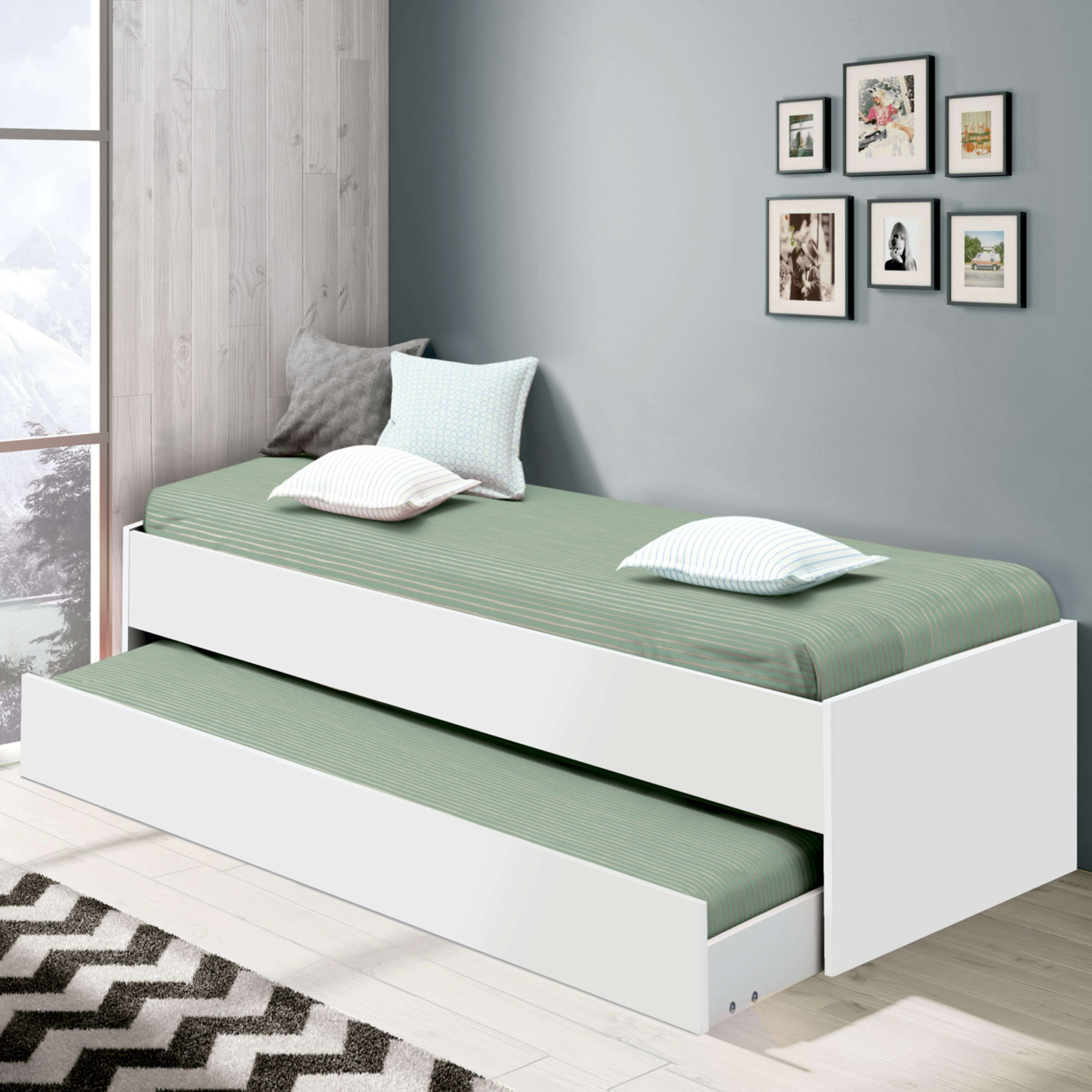 Una cama nido blanca con ropa de cama verde y almohadas se encuentra junto a una ventana con vistas a montañas.