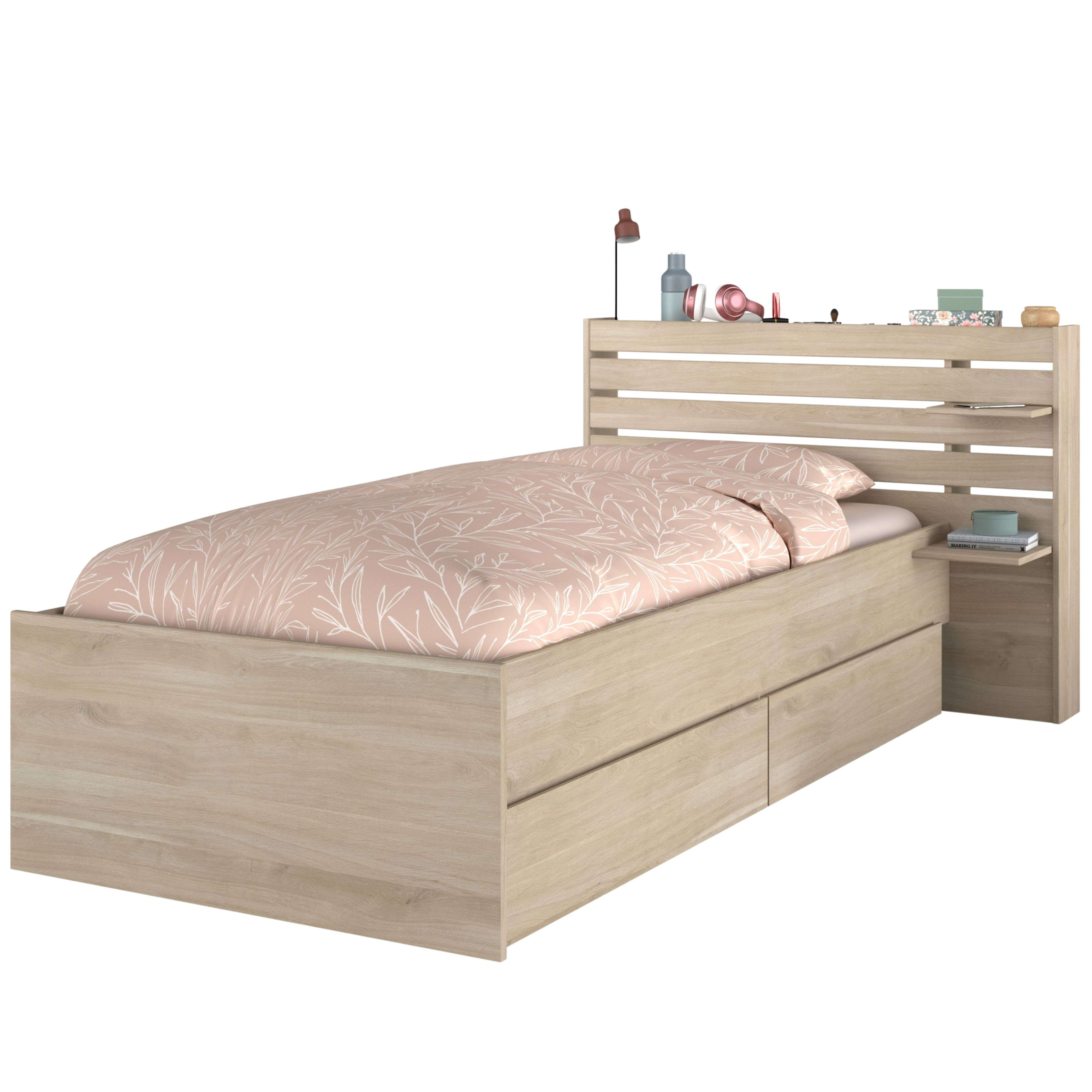 Cama de madera con ropa de cama de hojas rosas, mesita de noche y adornos.