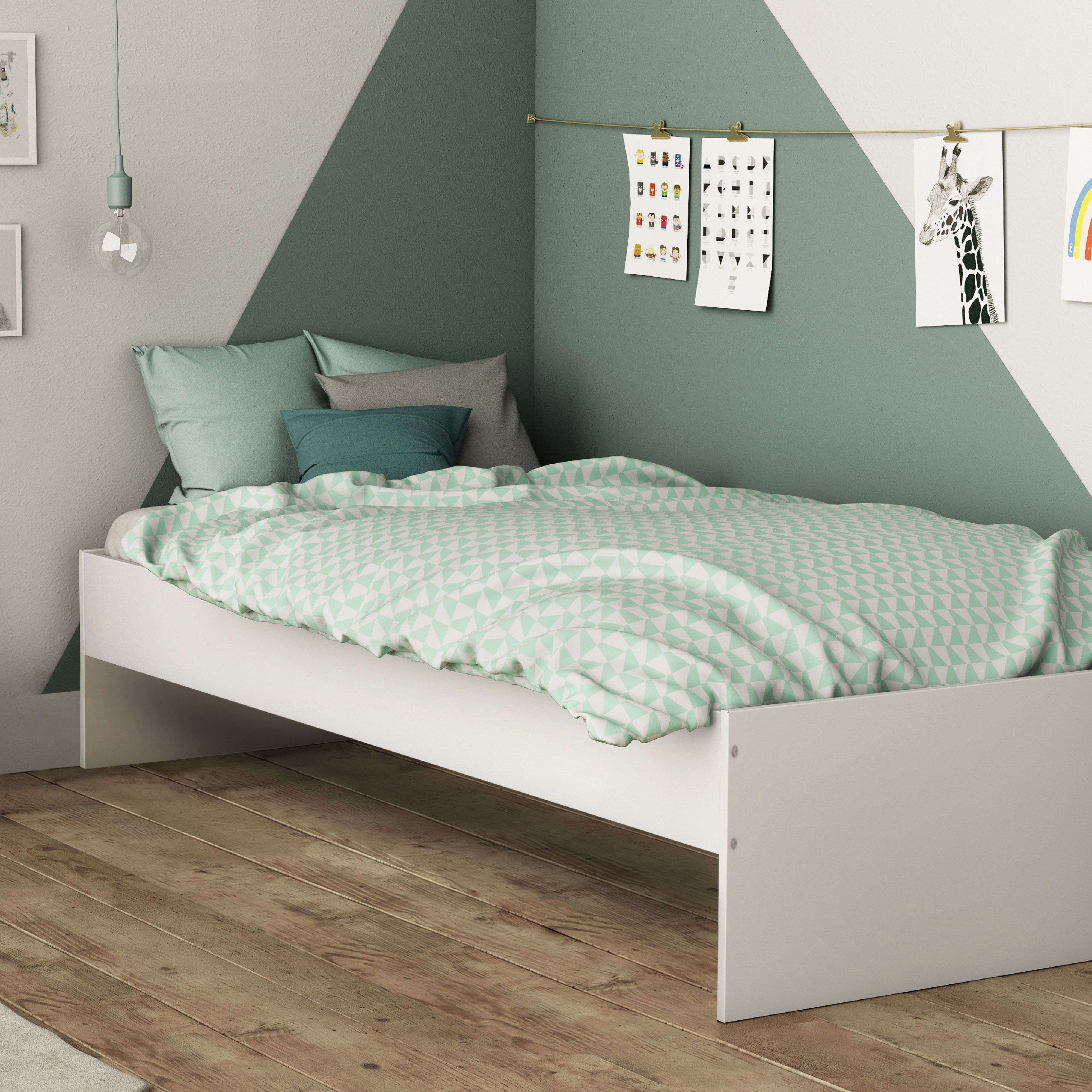 Una cama blanca con ropa de cama y almohadas verde menta en una habitación con paredes geométricas.