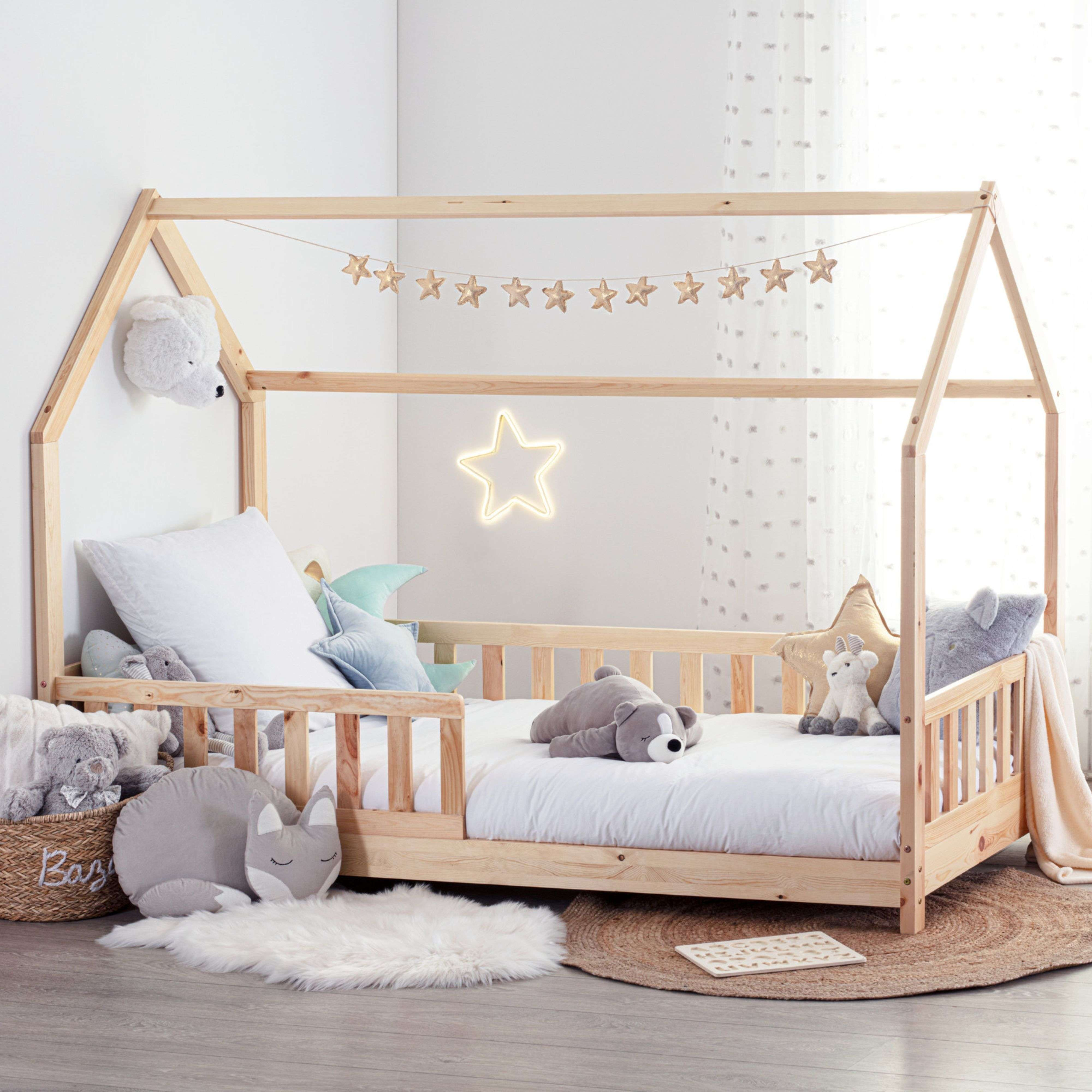 Cama tipo casa de madera con peluches, guirnalda de estrellas y luz de estrella neón.
