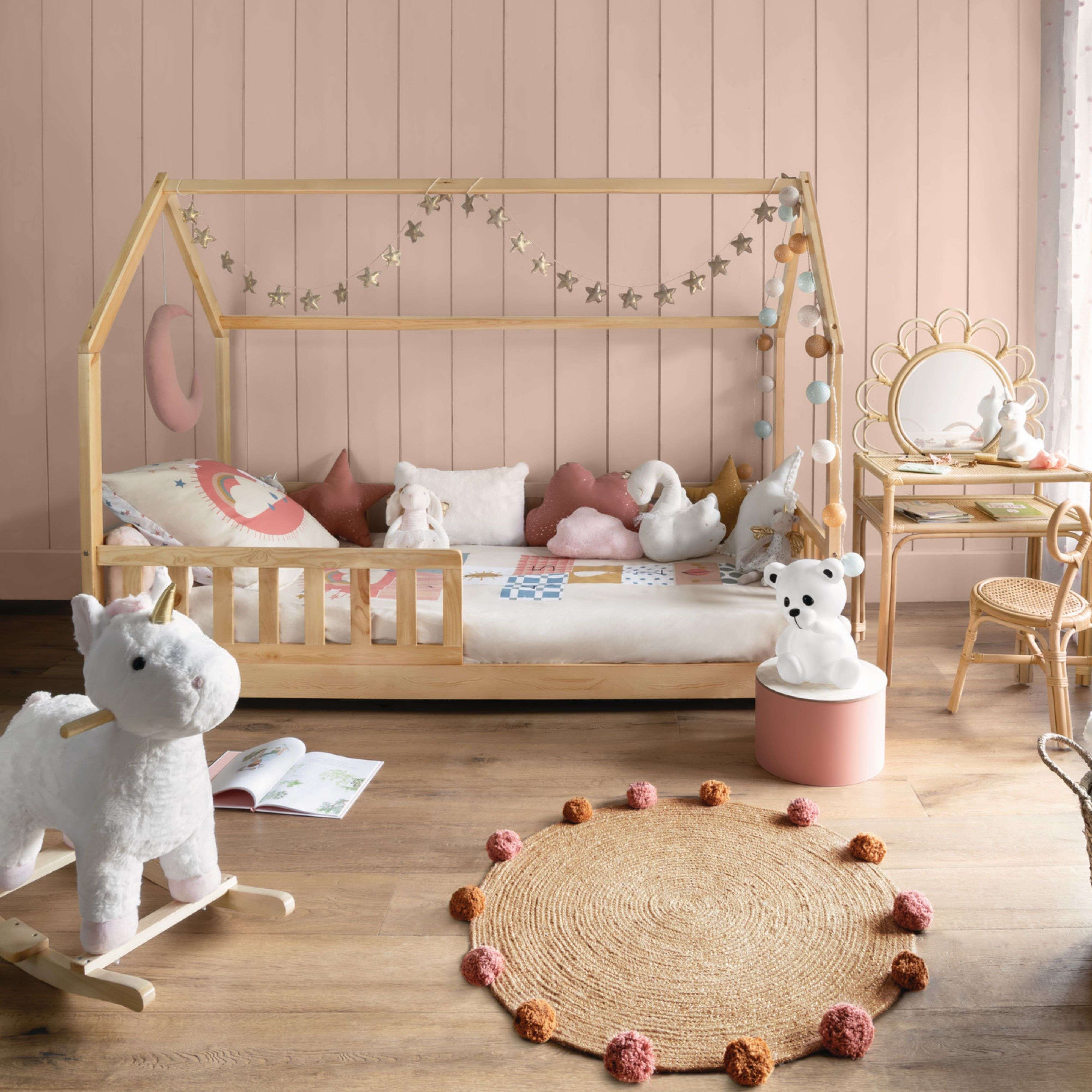 Habitación infantil con cama de madera, juguetes y alfombra redonda.