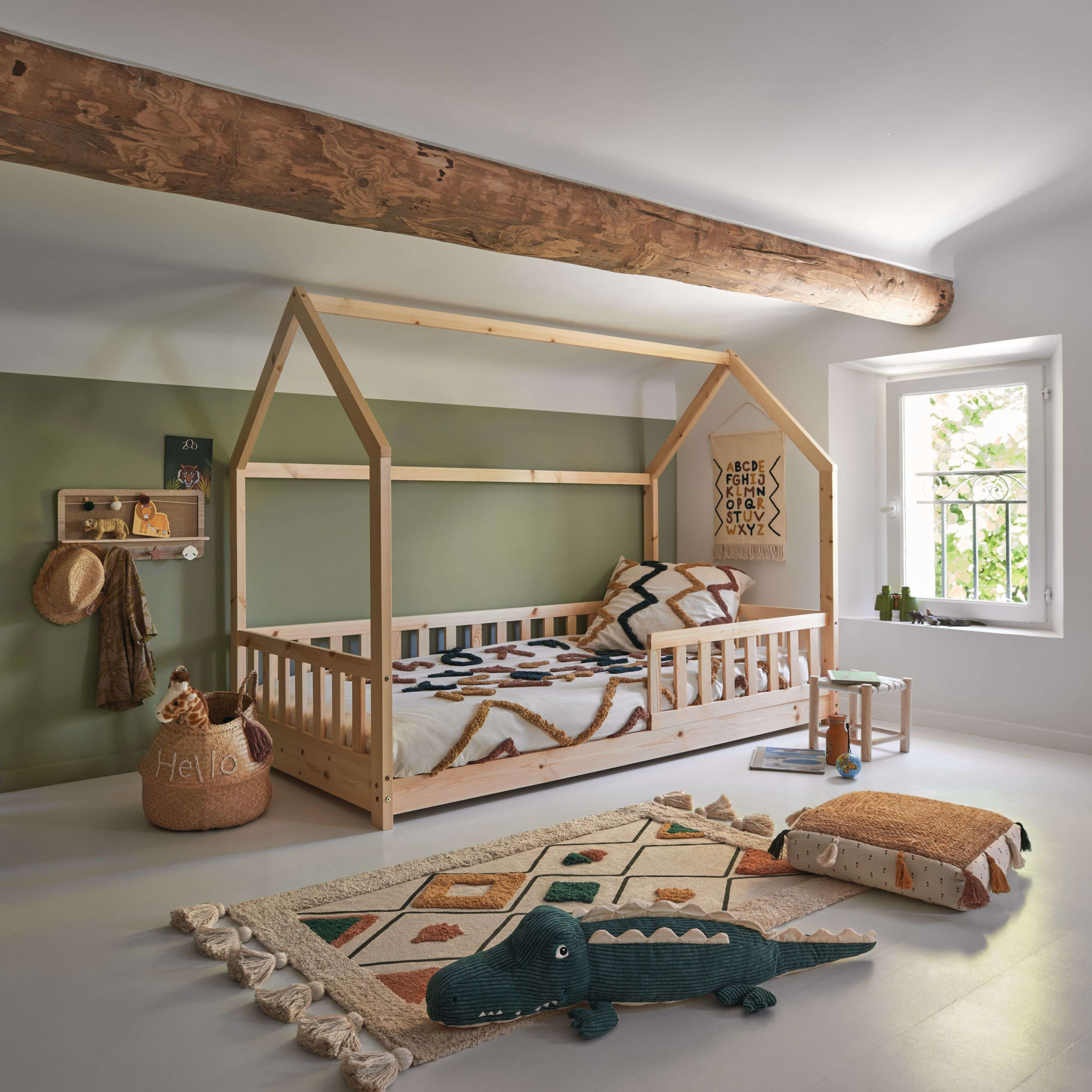 Habitación infantil con cama casita, alfombra, cojines y juguetes.