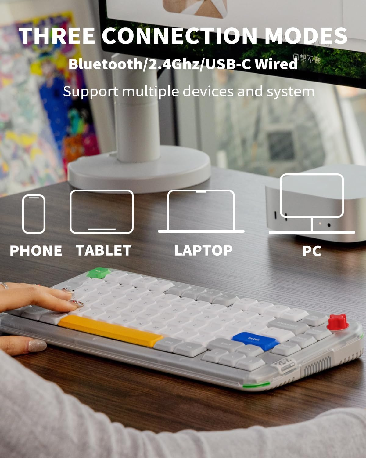 Osoba pisze na szarej klawiaturze z kolorowymi klawiszami i ikonami telefonu, tabletu, laptopa i komputera.