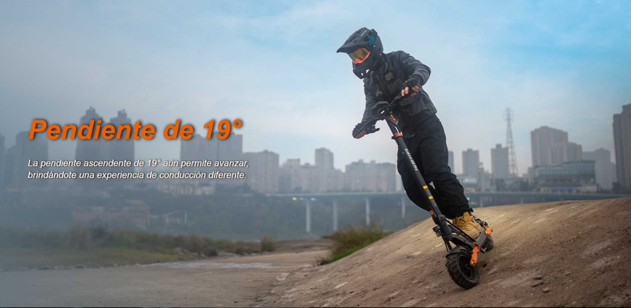 Una persona monta un patinete eléctrico por una pendiente. Ciudad al fondo.