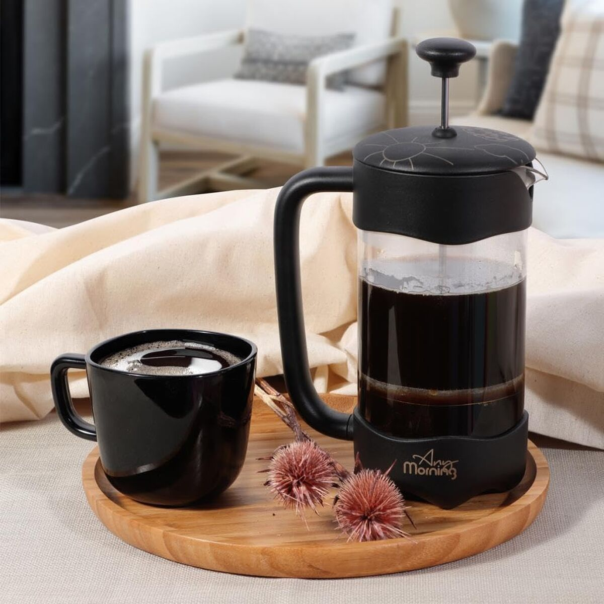 Una taza de café negra y una cafetera de prensa francesa con café en una bandeja.