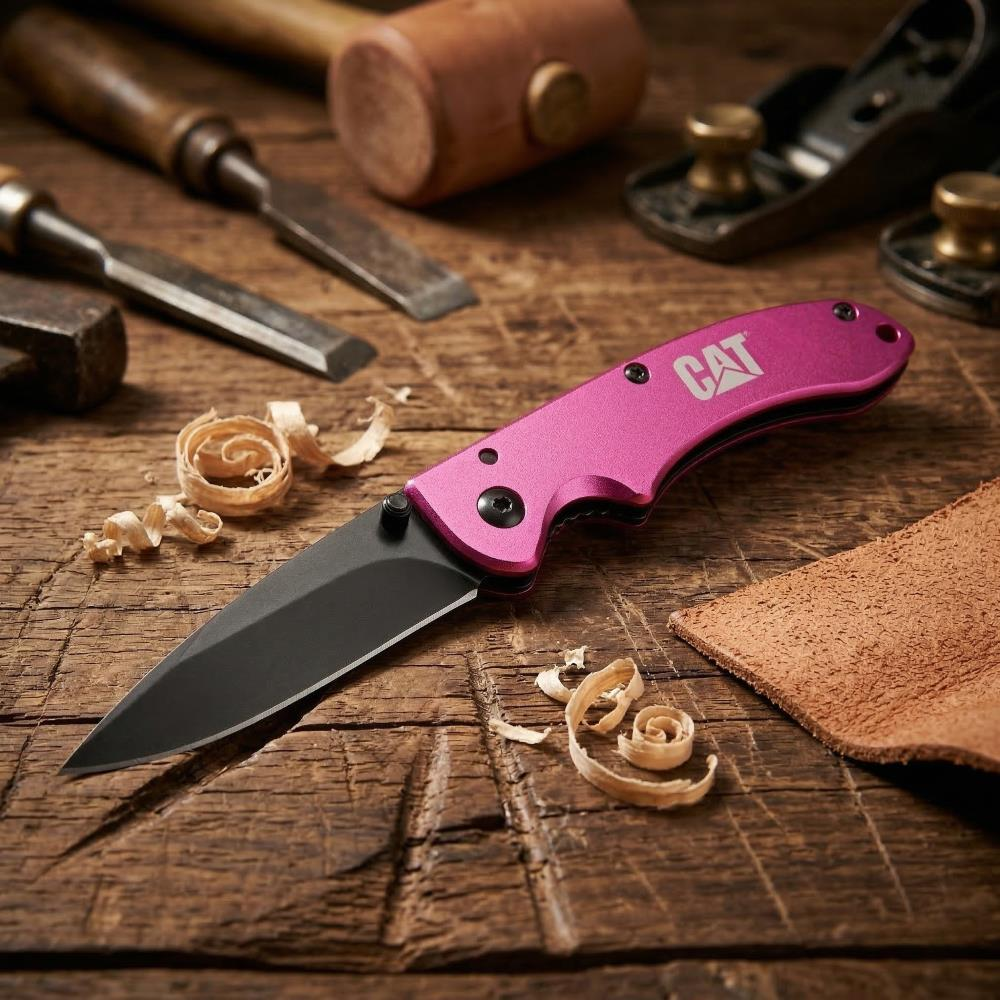 Pembe CAT bıçağı, keskiler, çekiç ve tahta talaşları ile ahşap masada.