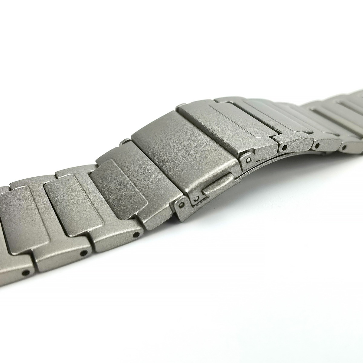 Un cinturino d'orologio in metallo grigio con maglie su sfondo bianco.