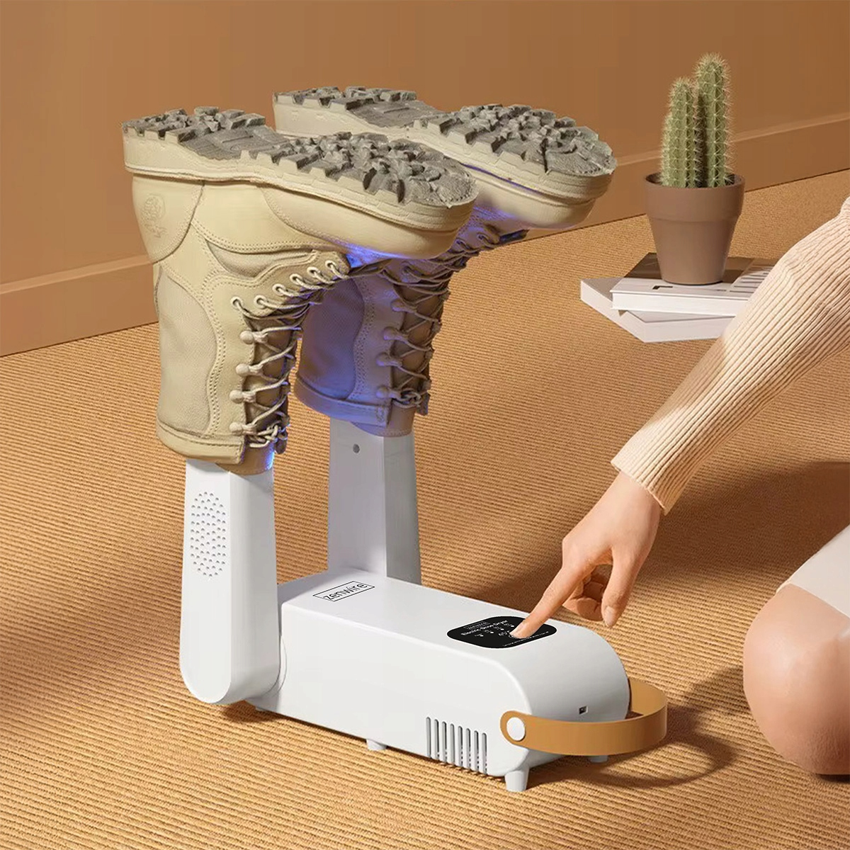 Biała suszarka do butów z dwoma butami skierowanymi do góry. Ręka obsługuje urządzenie.