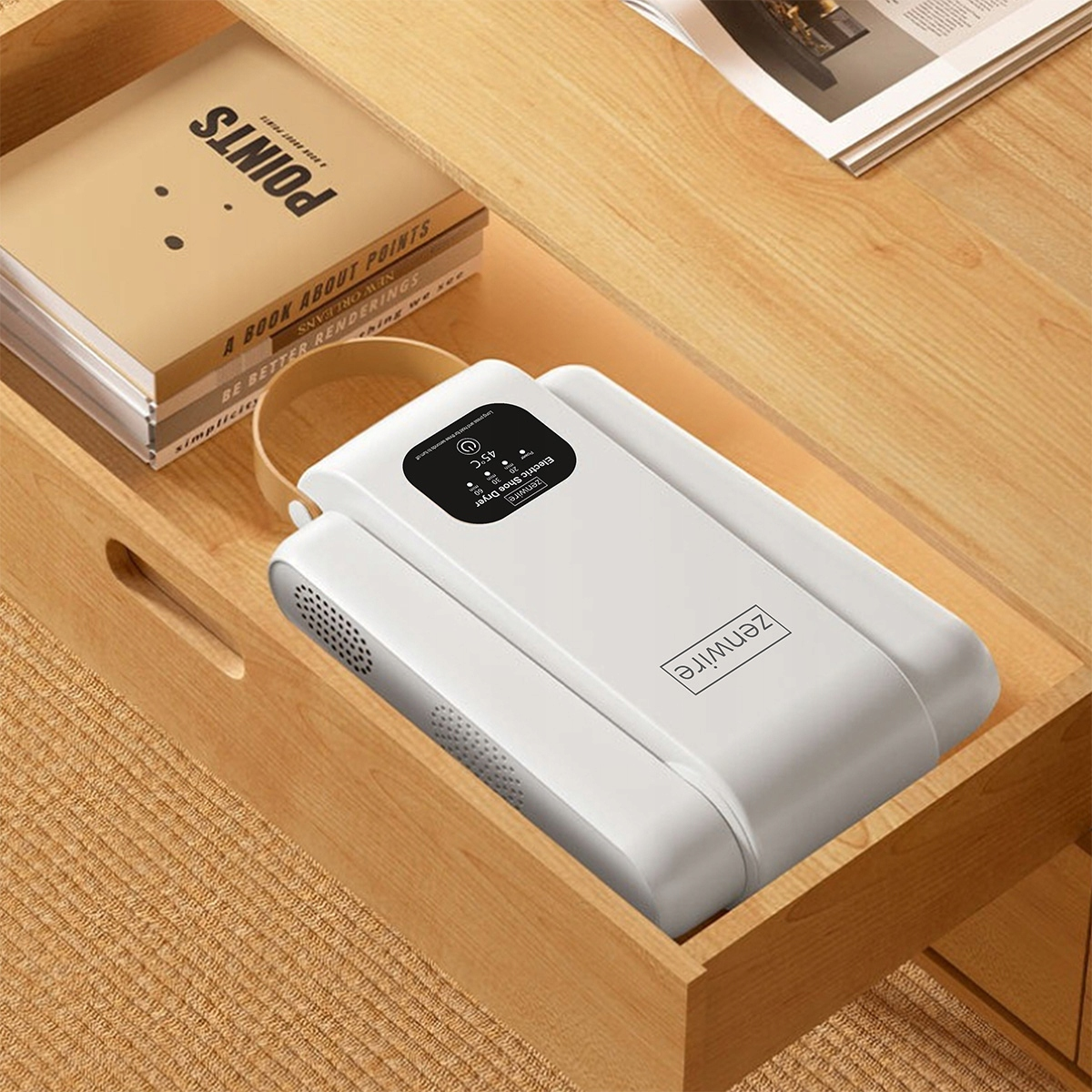 Biała elektryczna suszarka do butów Zenwire na drewnianej powierzchni obok książek.