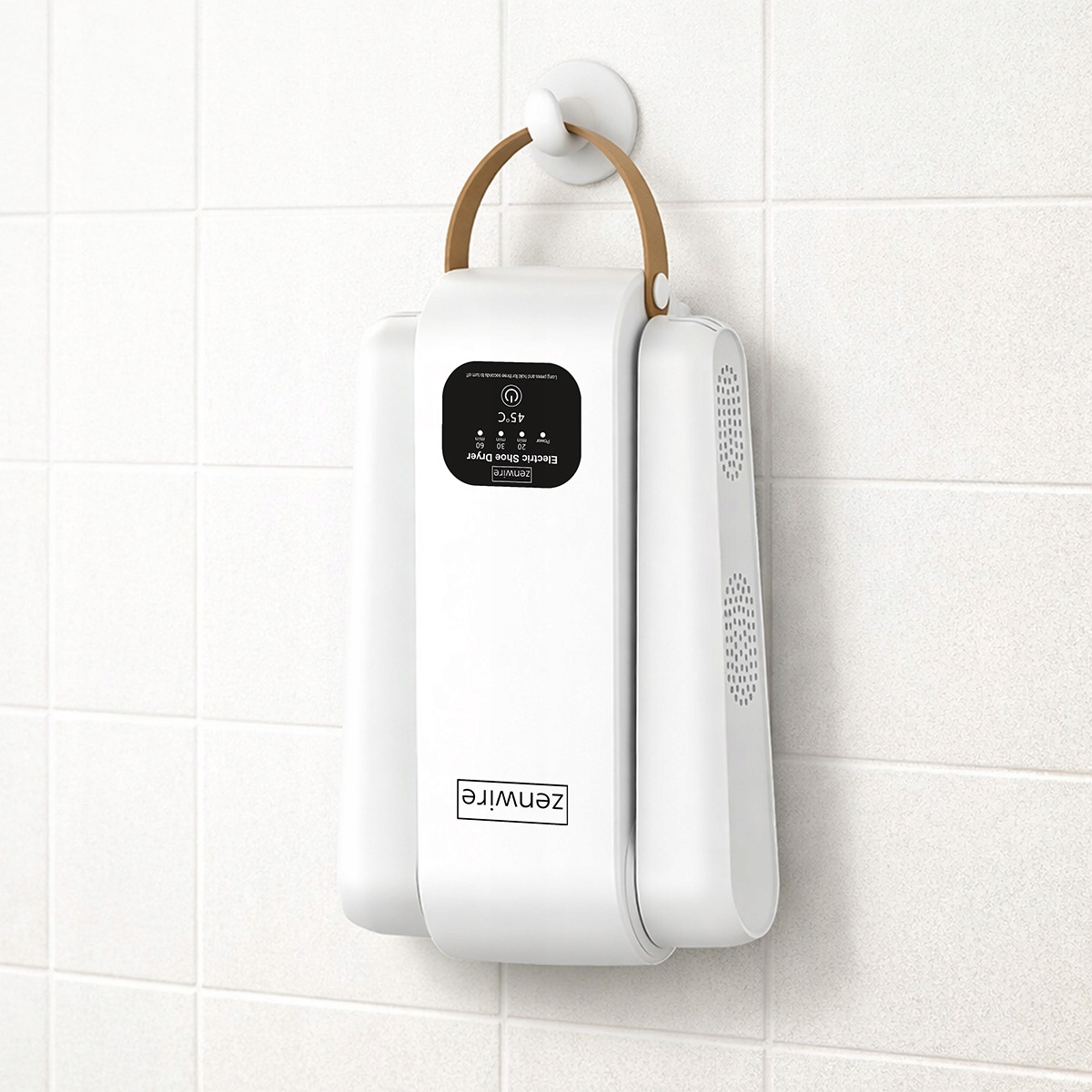 Biała elektryczna suszarka do butów z brązową rączką wisi na kafelkowanym ścianie.