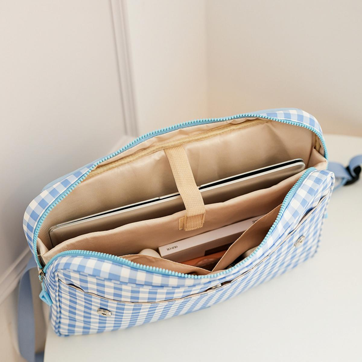 Eine blau-weiße Vichy-Tasche ist geöffnet und zeigt ein Tablet und ein Buch.