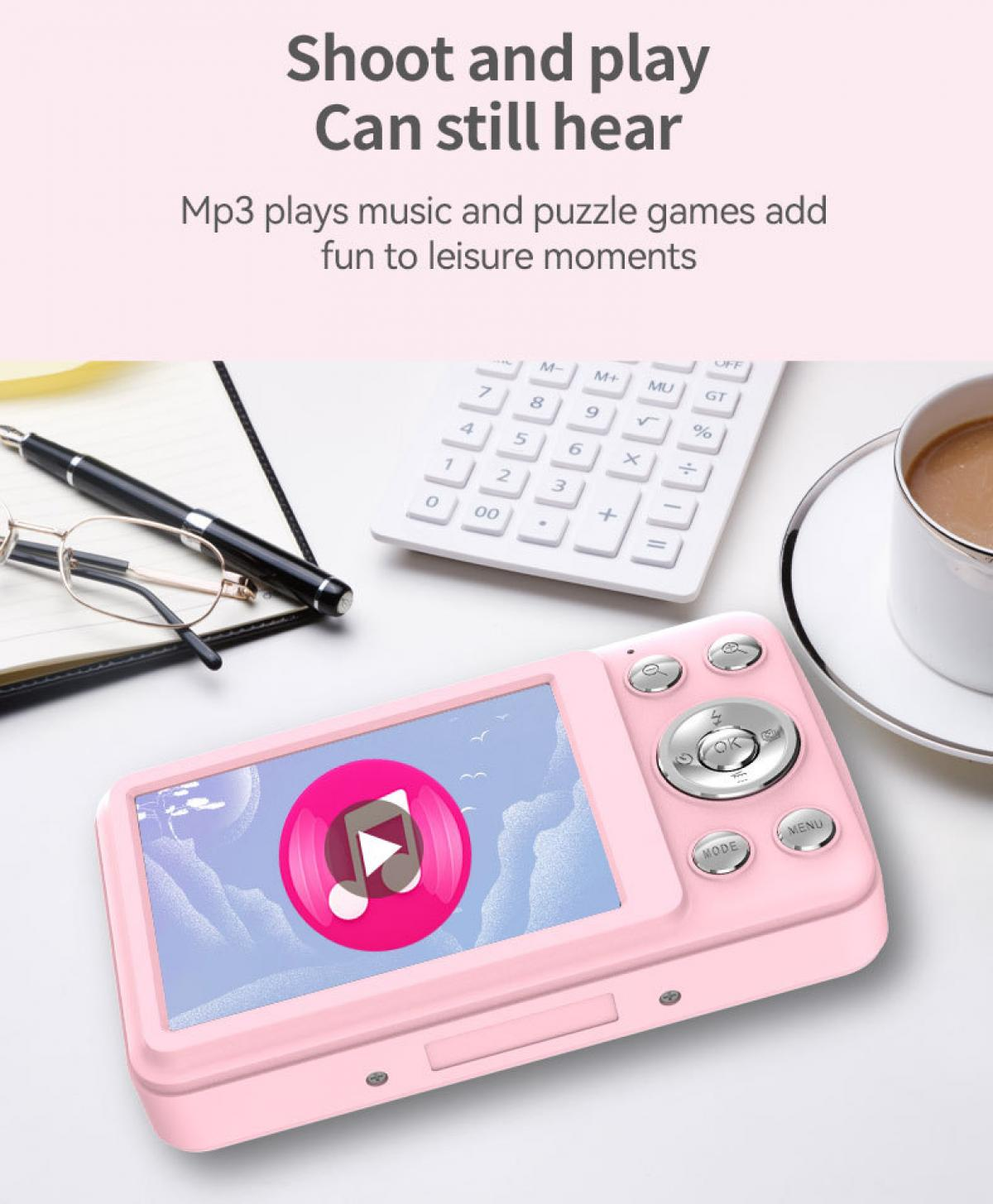 Rosa Digitalkamera mit Musik-Symbol auf dem Bildschirm, Taschenrechner, Brille, Stift, Notizbuch und Kaffee.