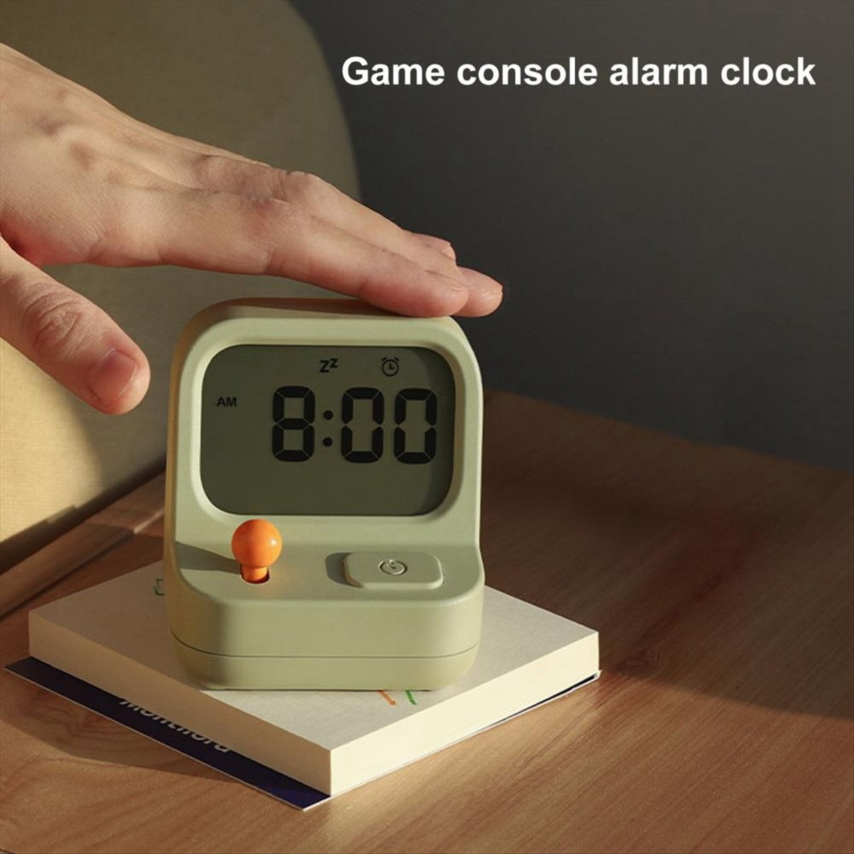 Eine Hand bedeckt eine grüne Spielkonsolen-Wecker-Uhr, auf der 8:00 steht.