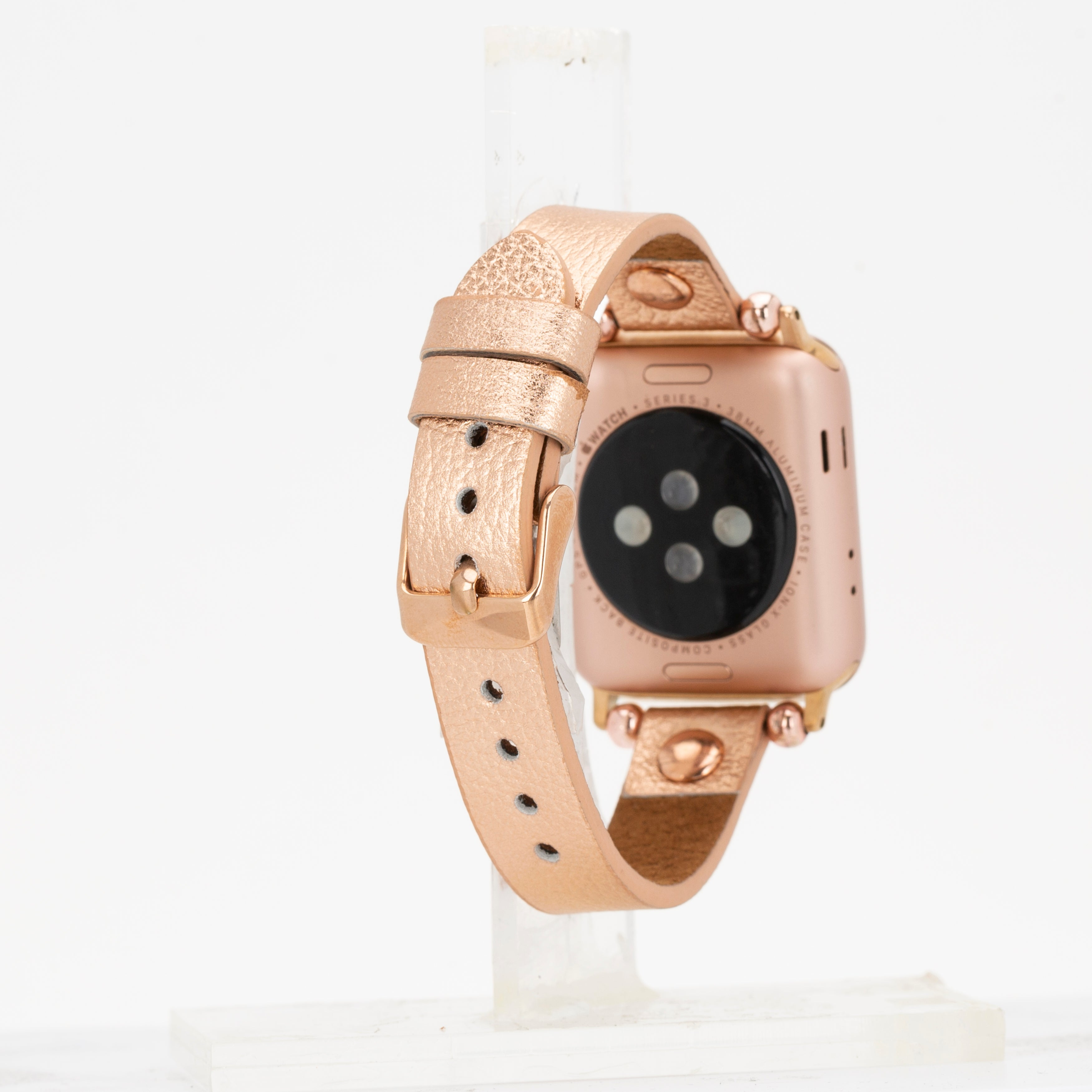 Dokuya sahip deri kordonlu, gül altın rengi Apple Watch, stant üzerinde sergileniyor.
