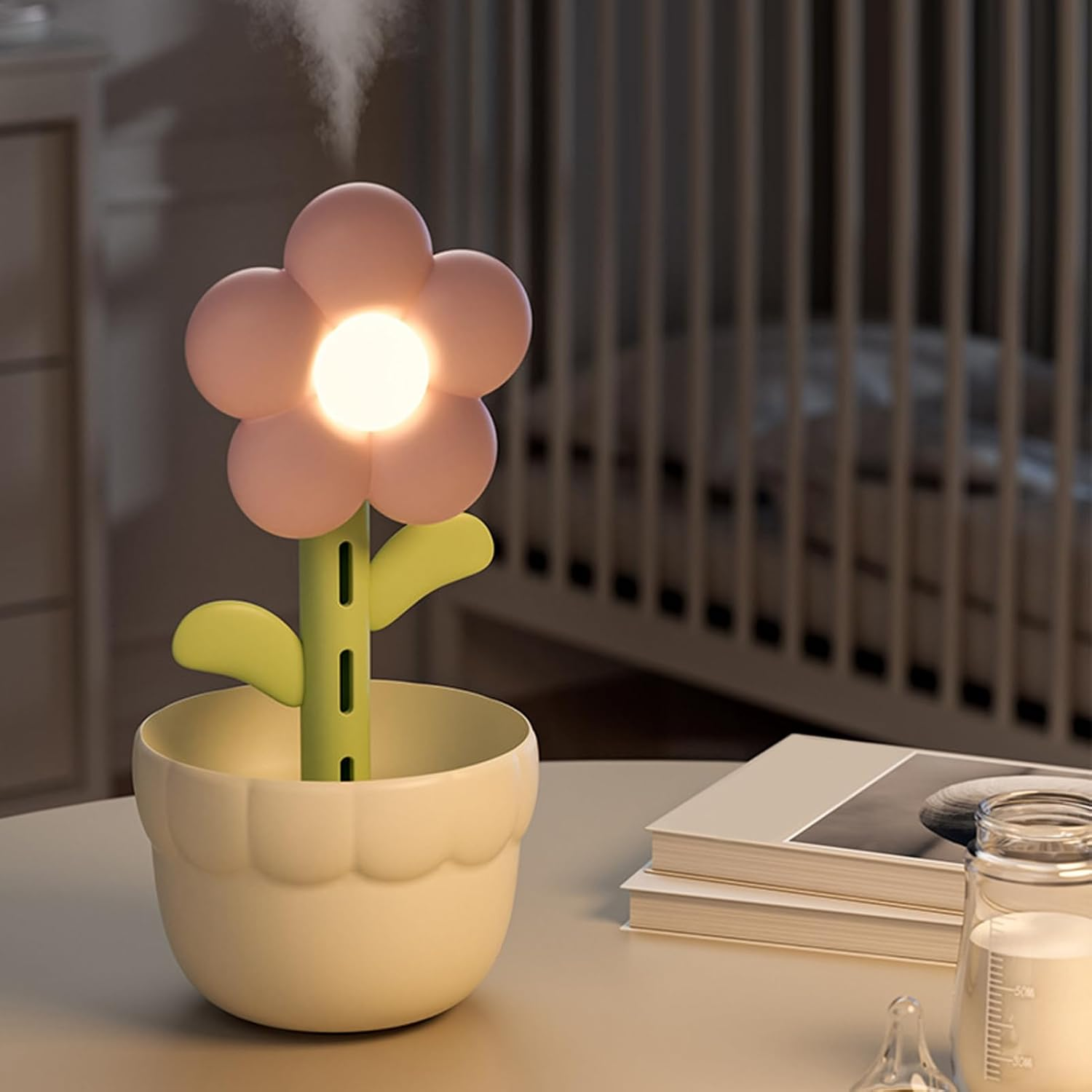 Ein blumenförmiger Luftbefeuchter gibt Nebel ab, steht in einem Topf neben Büchern und einer Babyflasche.