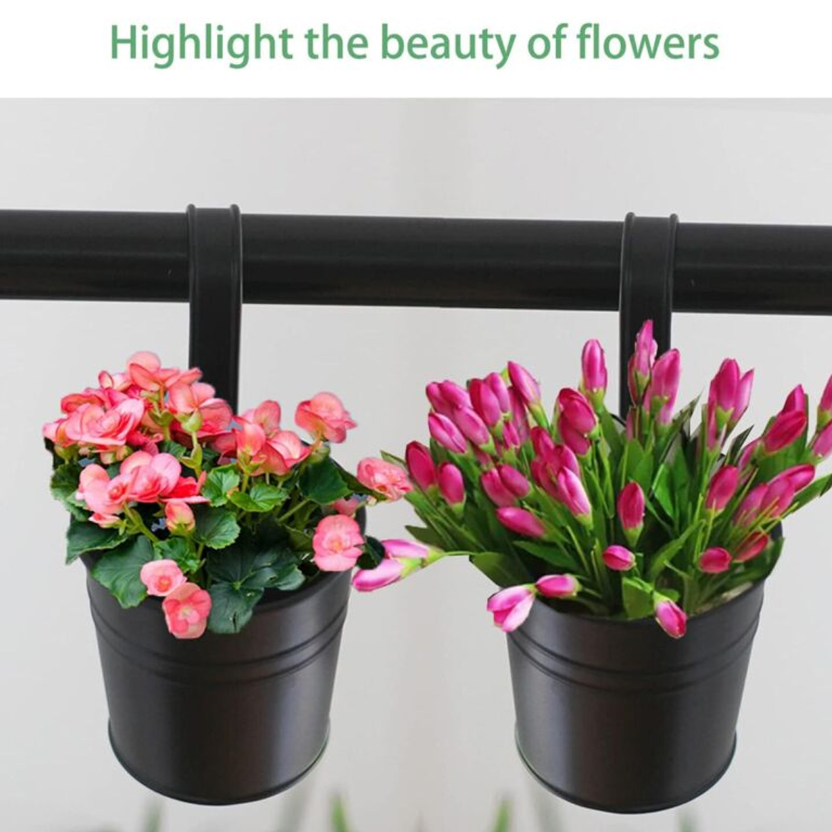 Zwei dunkle Pflanzgefäße mit rosa Blumen hängen an einer dunklen Stange. Eines hat offene Blüten, das andere Knospen.