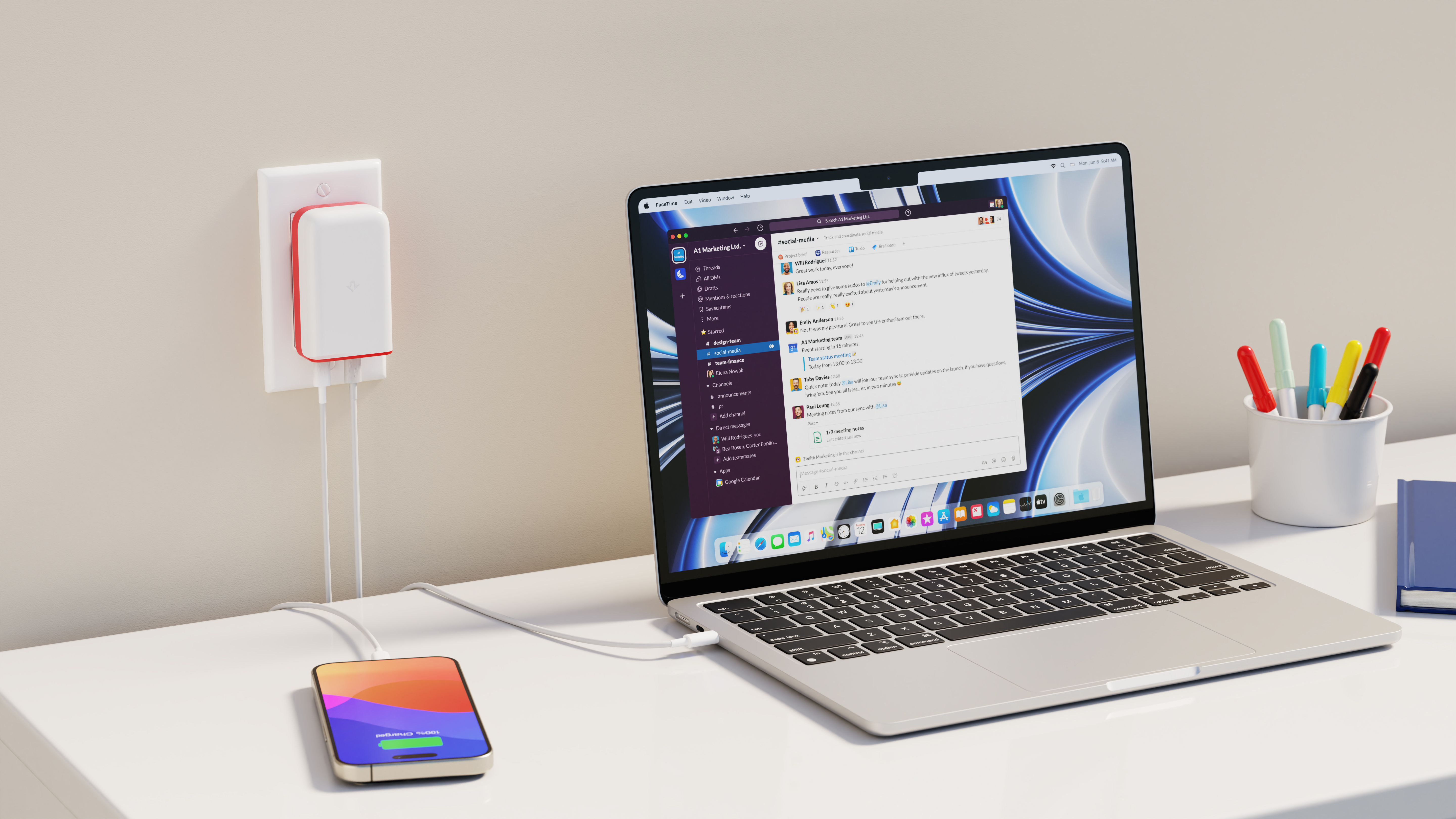 Laptop aperto su Slack, telefono in carica, caricabatterie collegato.