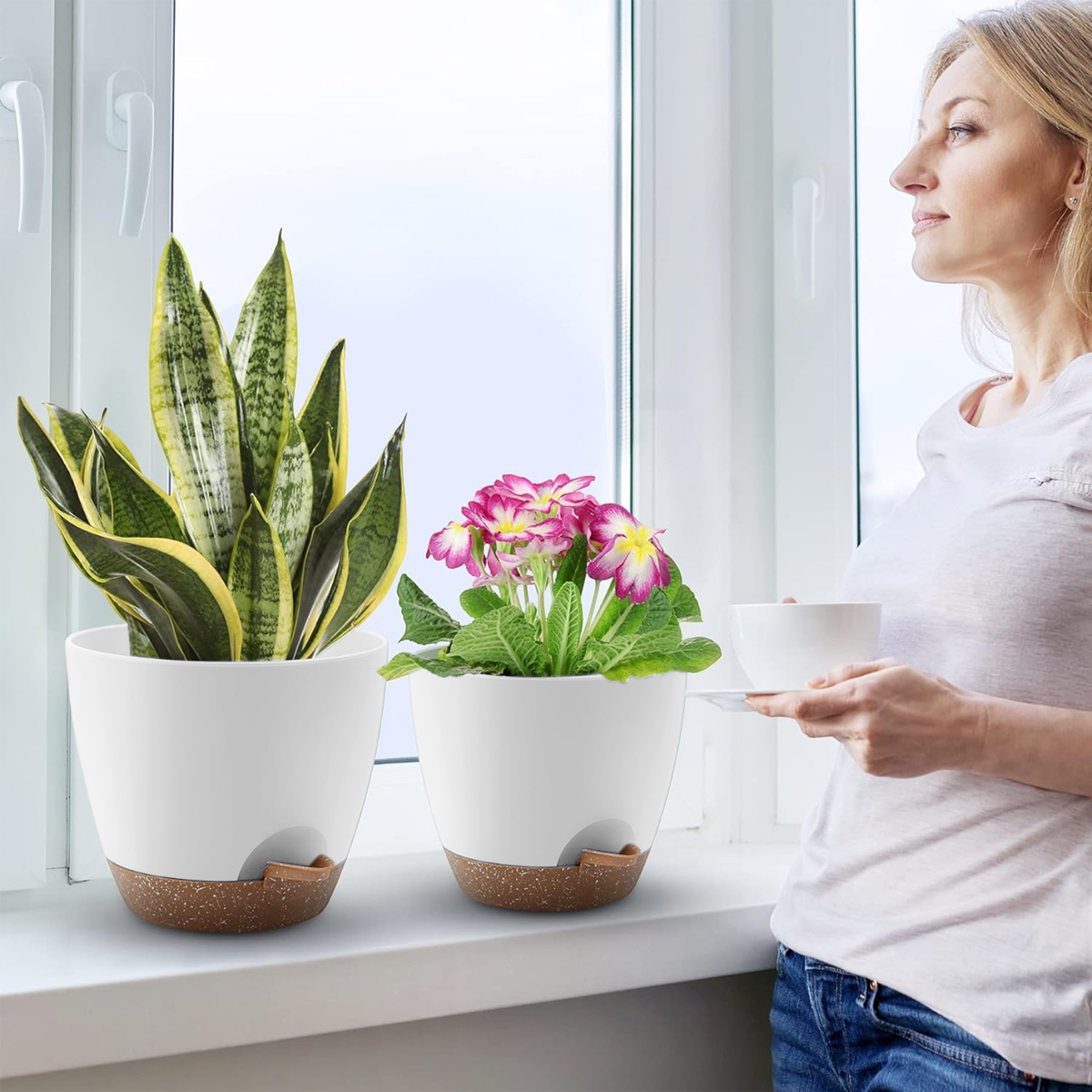 Frau trinkt Kaffee am Fenster mit zwei Topfpflanzen.