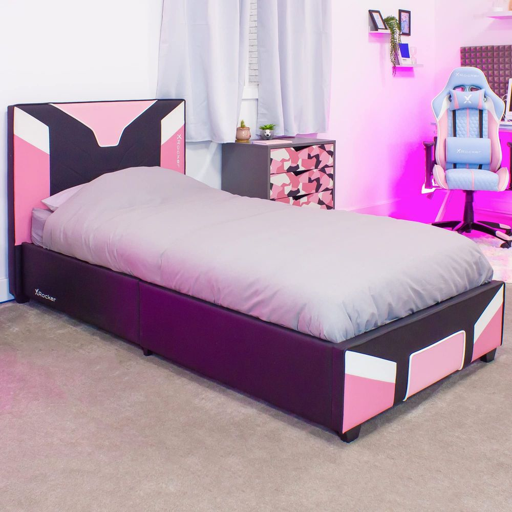 Un letto rosa e nero con piumone grigio, accanto a un comodino mimetico.