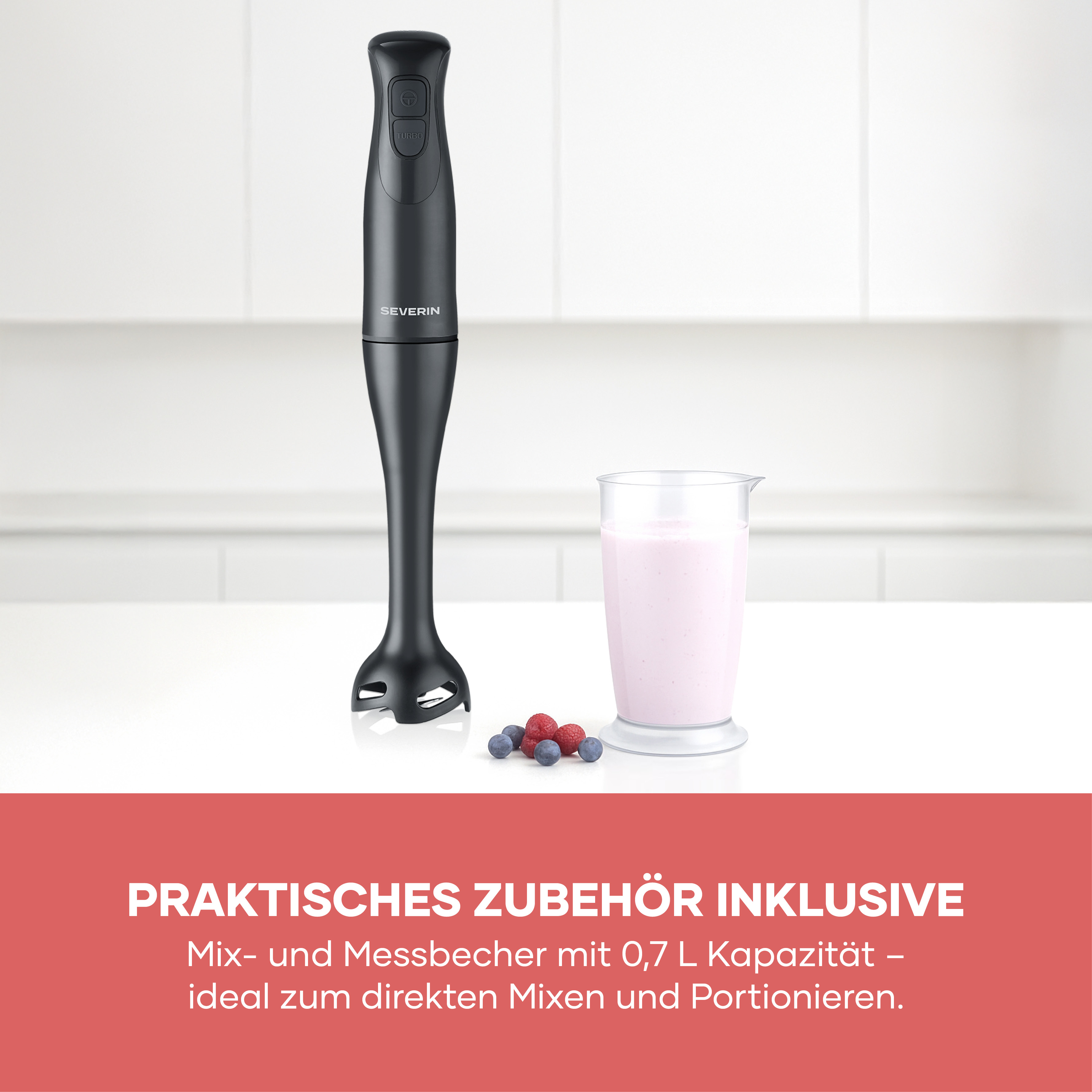 Schwarzer Stabmixer mit Beeren und einem Glas Milchshake auf weißer Arbeitsplatte.