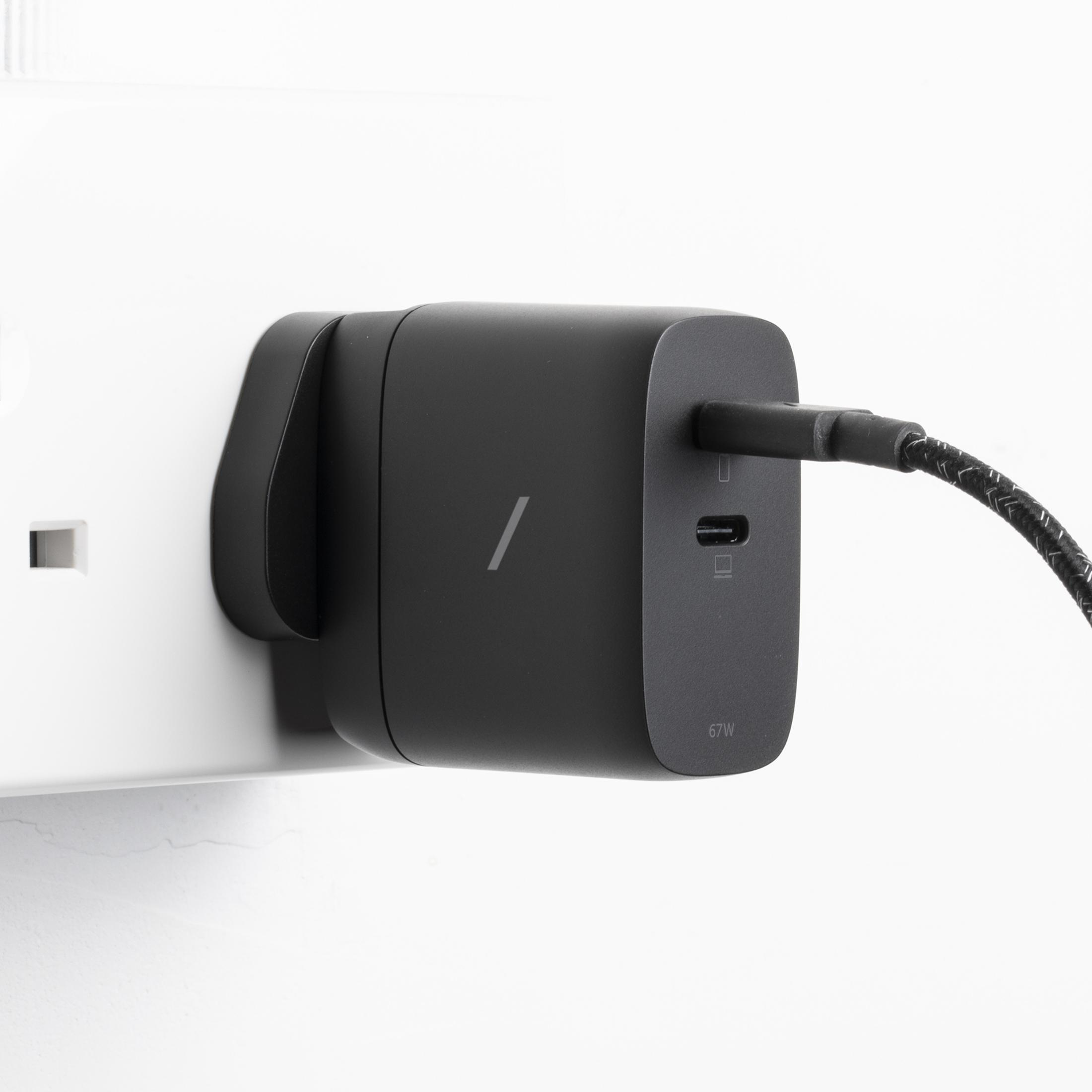 Adattatore di alimentazione nero con cavo USB-C collegato a una presa a muro.