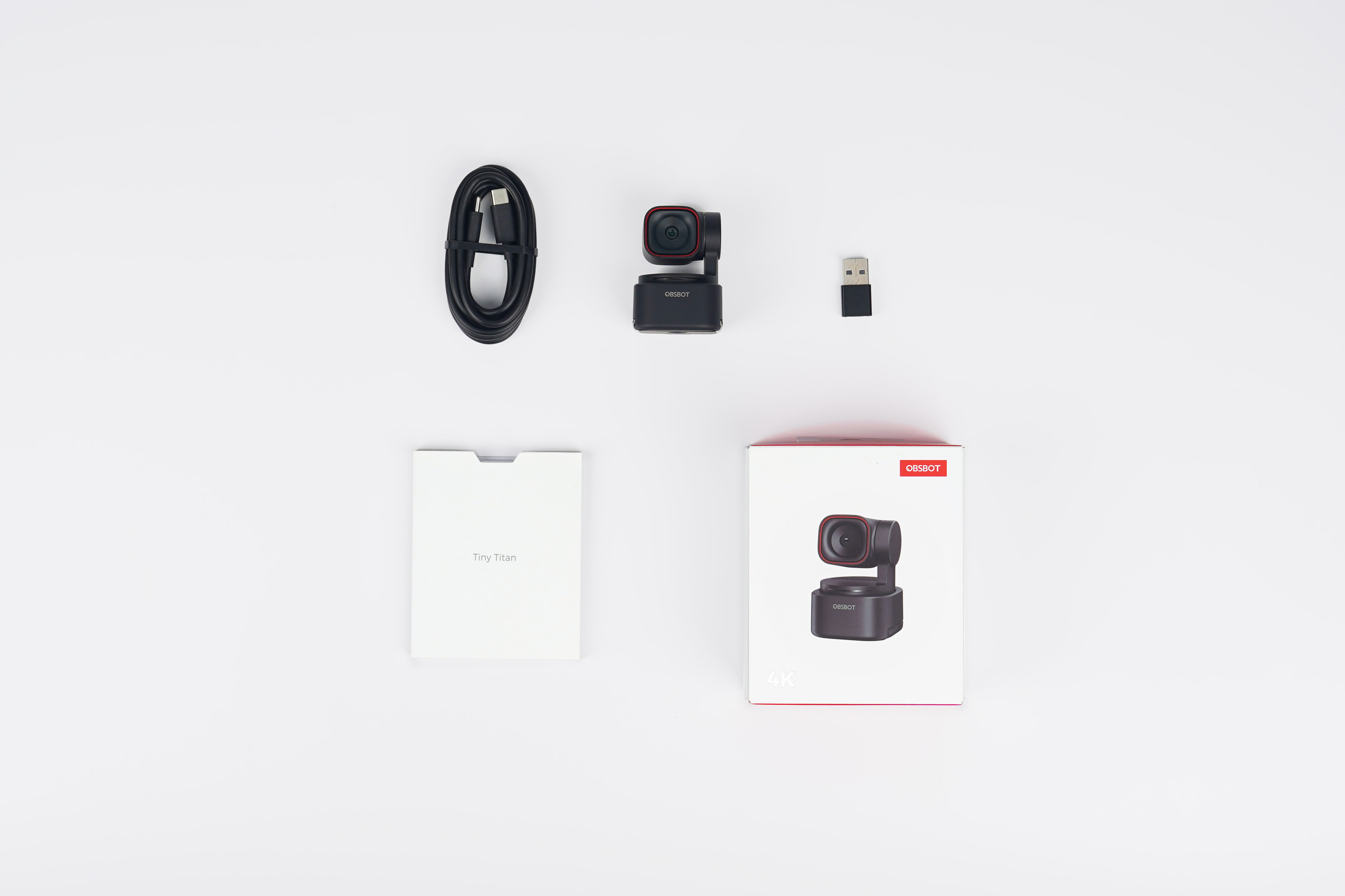 Un cavo nero, una fotocamera, un adattatore USB, una scatola e un manuale.