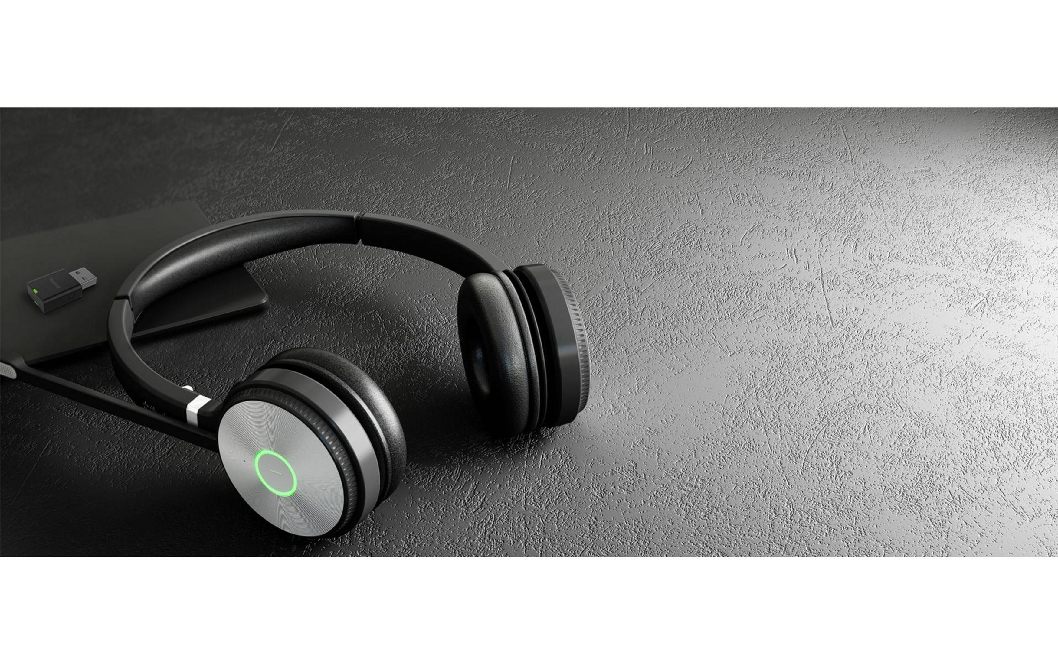 Black wireless headphones with microphone and USB dongle on a dark textured surface.