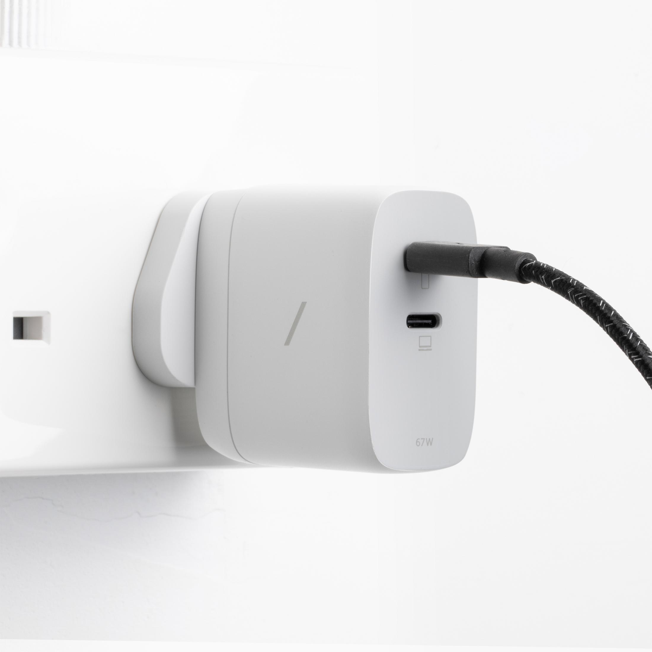 Ein weier USB-C-Adapter mit einem schwarzen Kabel, das an einer Wandsteckdose angeschlossen ist.