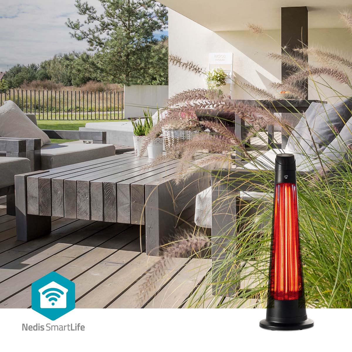 Een rode terrasverwarmer staat naast groen gras op een houten dek.