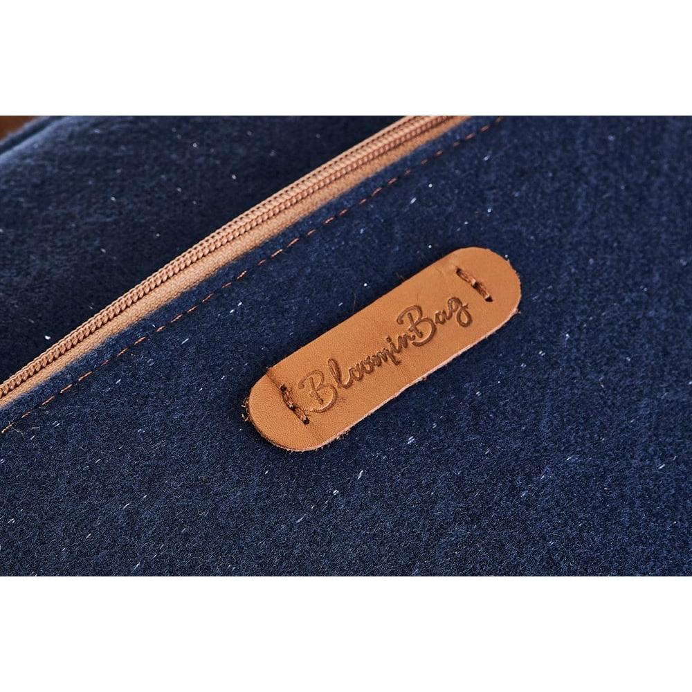 Fermuarlı mavi kumaş çanta üzerinde "Bloomin Bag" yazan kahverengi deri etiket.
