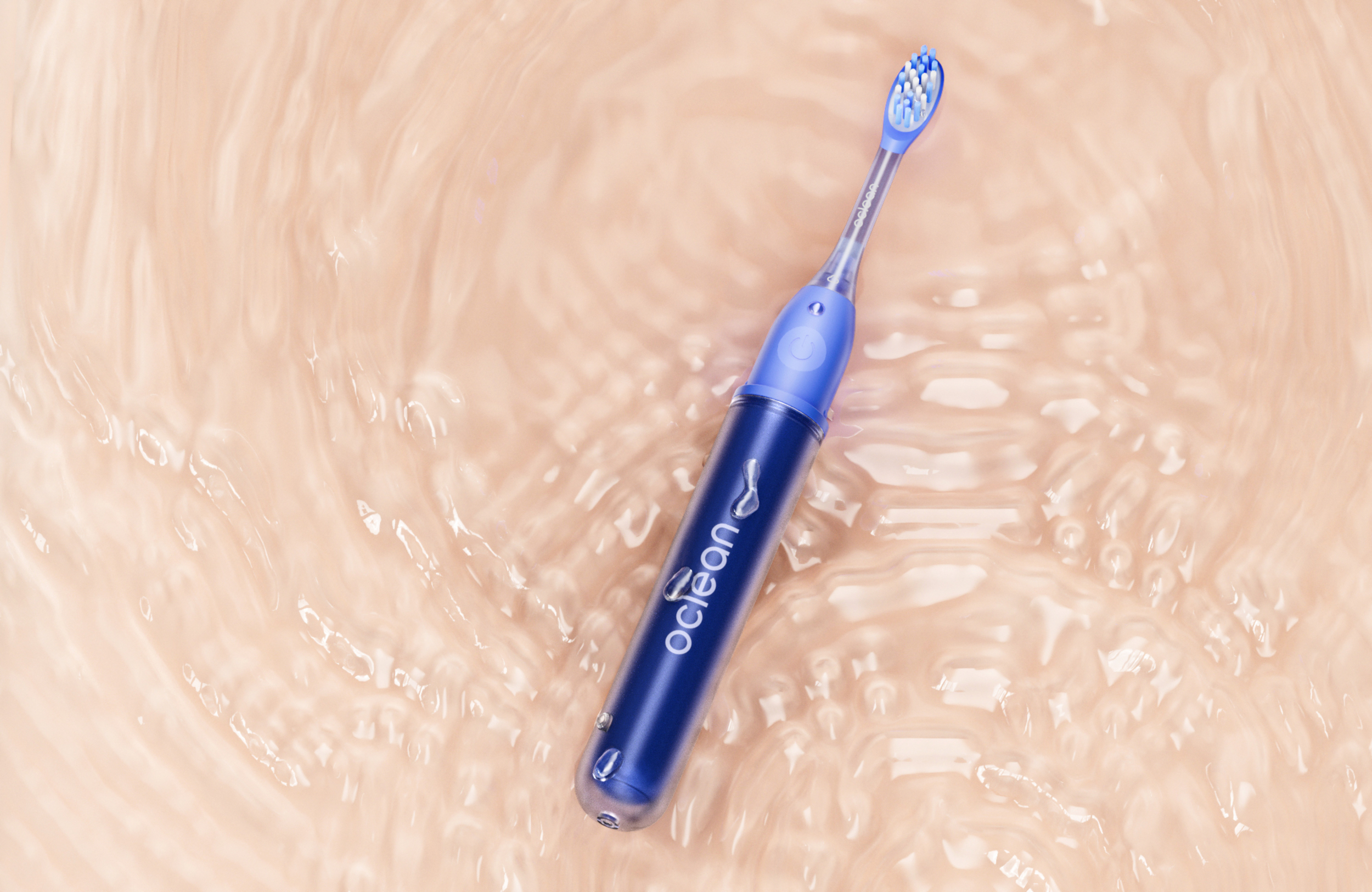 Spazzolino blu con setole bianche e blu su una superficie liquida beige chiaro.
